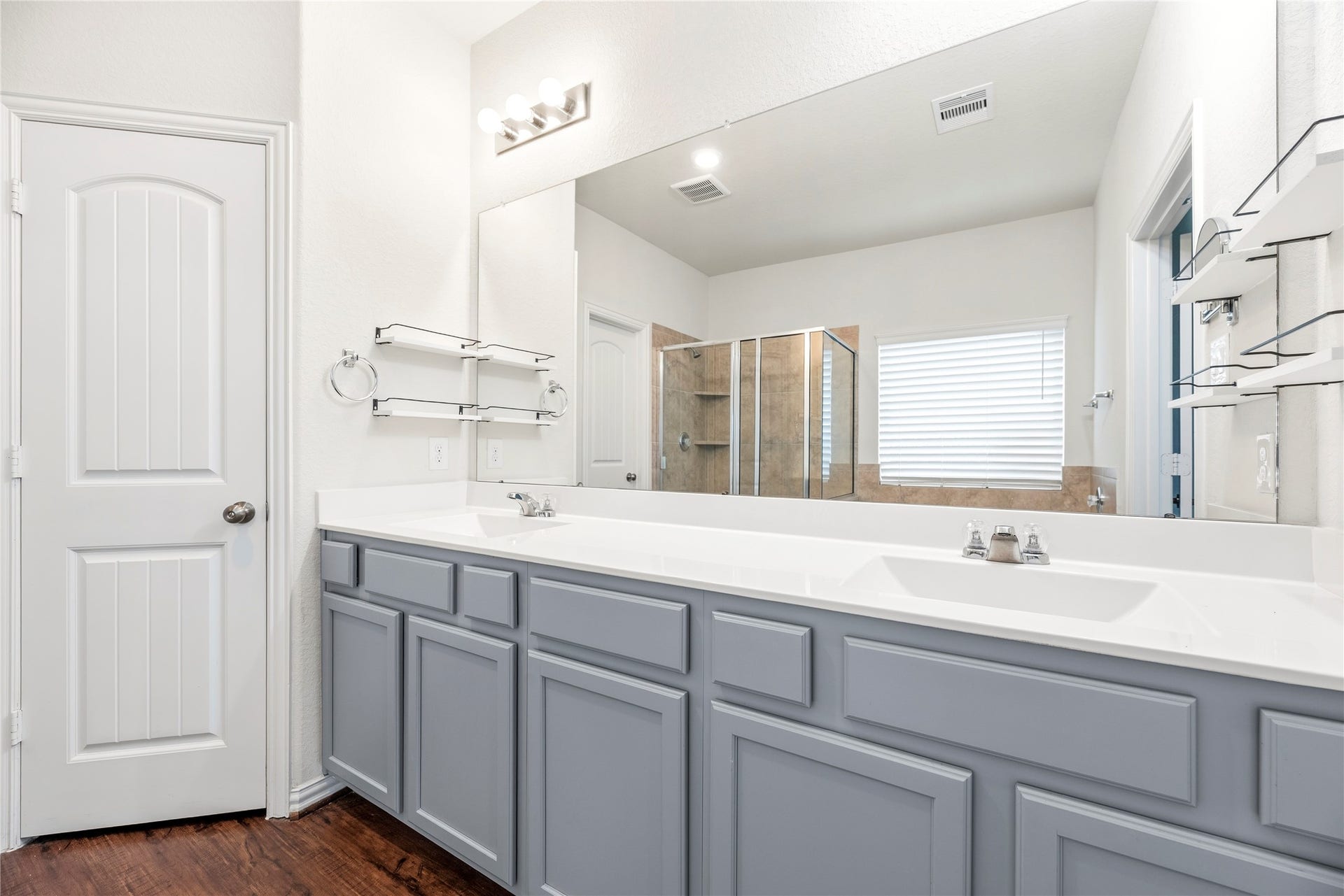 6418 Shadowbrook Hollow Trail, Katy, TX 77493 The primary bathroom showcases a extended custom vanity finished with cool gray cabinetry, dual integrated sinks, and polished hardware. A wall-to-wall mirror reflects the bright multi-bulb vanity lighting across the space.