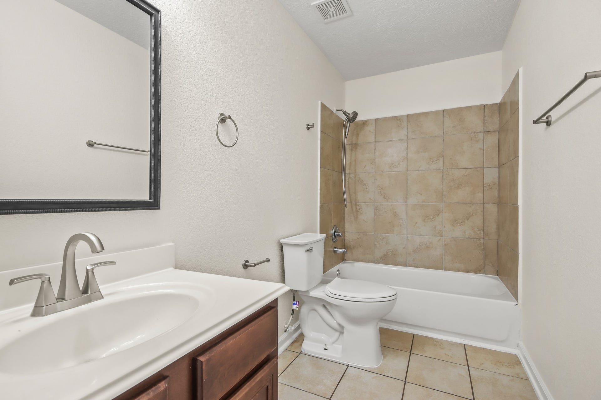 255 Silky Leaf Drive, Houston, TX 77073 Secondary bathroom featuring granite countertops and backsplash, tile floors, a framed mirror, and a shower/tub combo.
