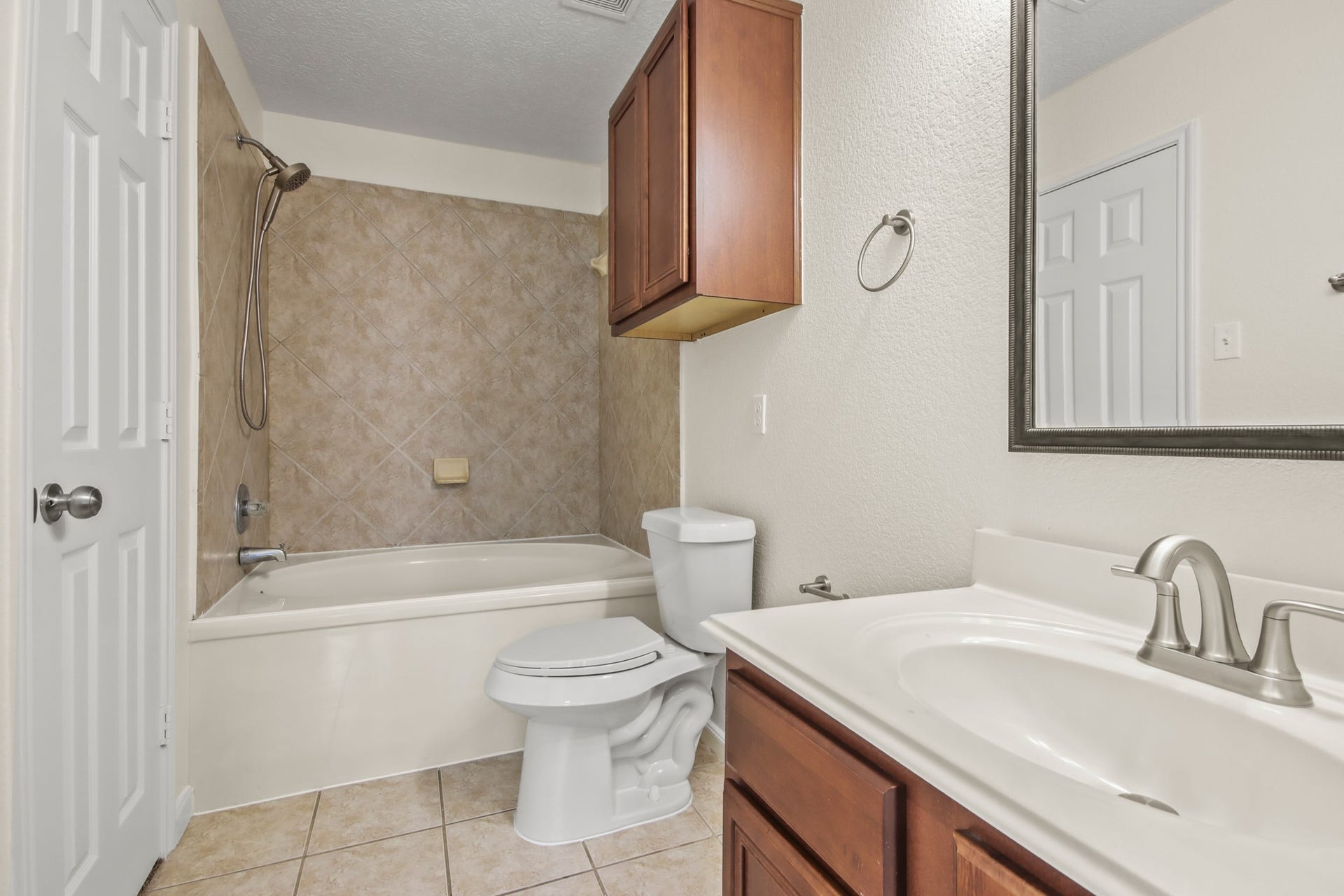 255 Silky Leaf Drive, Houston, TX 77073 The master bathroom features warm wood cabinetry paired with sleek countertops, a framed mirror, and a convenient shower/tub combination, offering both style and functionality. It is complete with a spacious built-in closet.