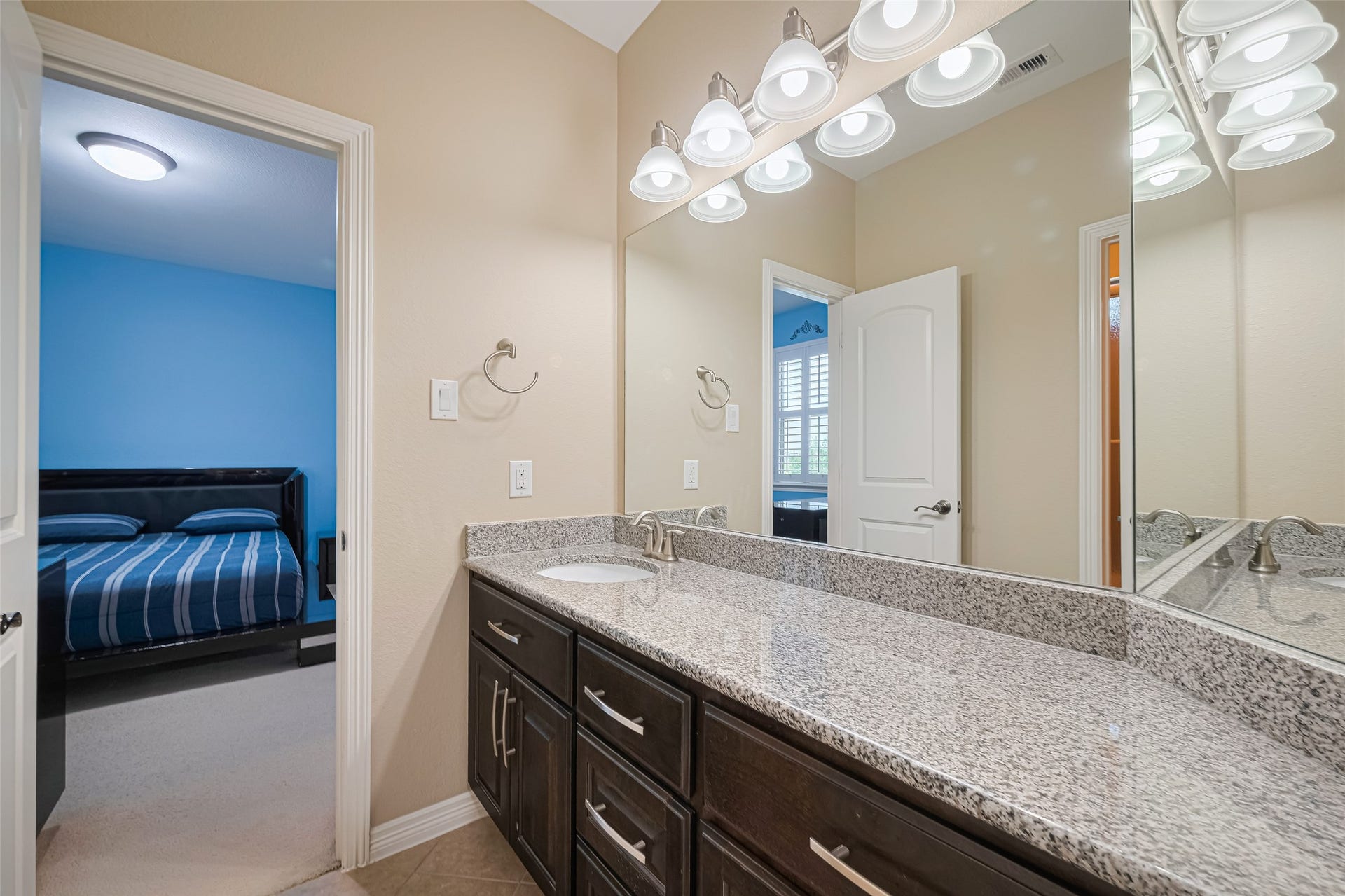 4722 Burclare Court, Sugar Land, TX 77479 Bathroom featuring a spacious granite vanity, dark cabinetry, expansive mirror, and convenient access from the adjoining bedroom.