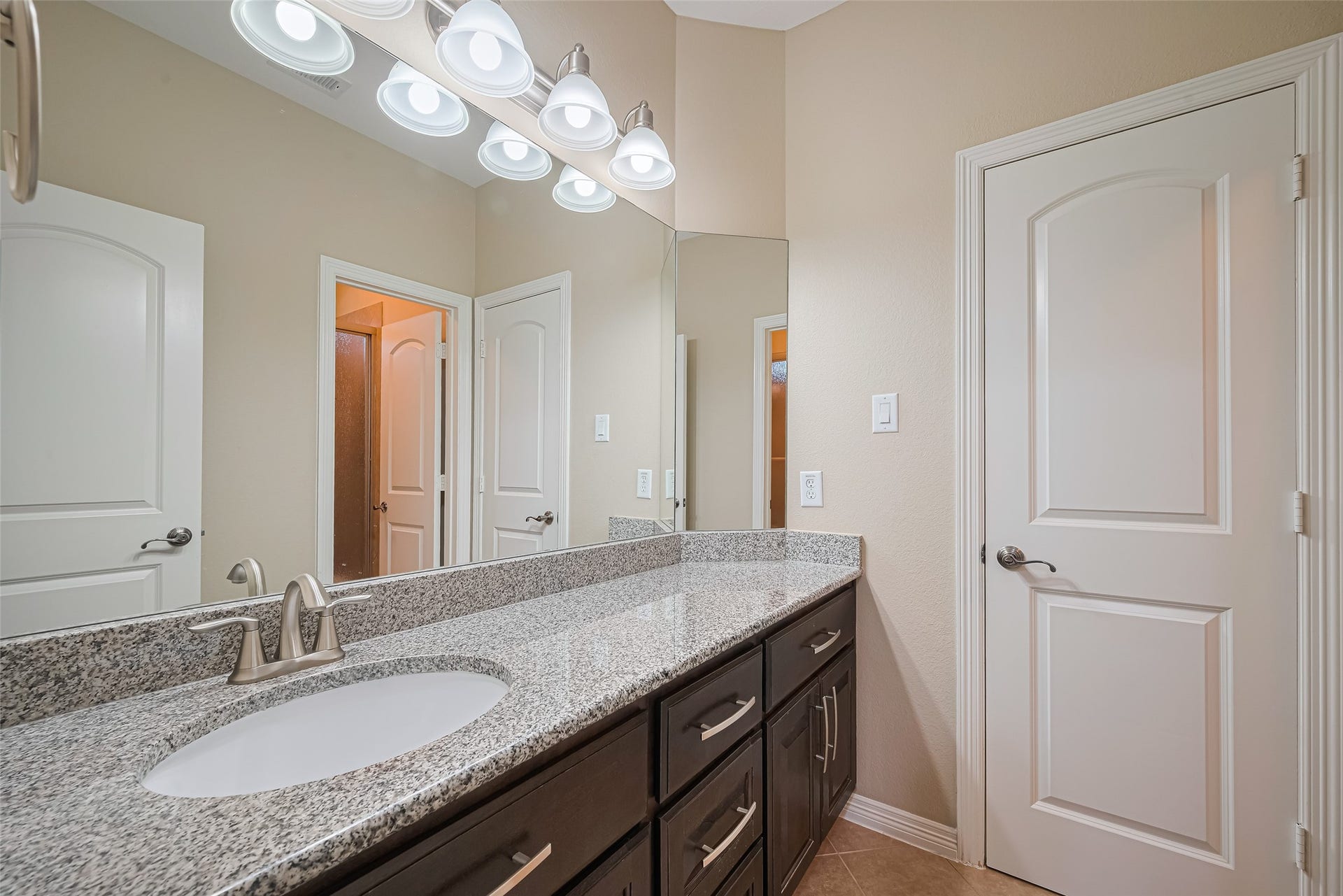 4722 Burclare Court, Sugar Land, TX 77479 Well-appointed secondary bathroom featuring a spacious granite vanity, dark cabinetry, expansive mirror, and bright vanity lighting.