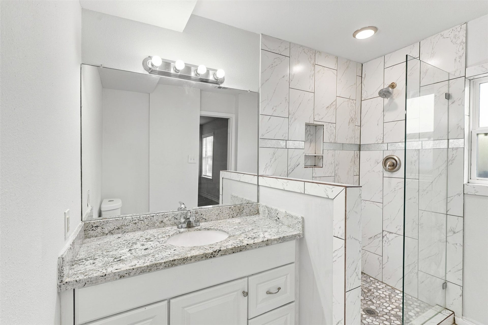 What a beautiful primary bathroom! Featuring an elegant granite countertop, a spacious vanity with ample storage, and a lovely tiled walk-in shower with glass enclosure, this refreshing space offers a wonderful place to start your morning and unwind at the end of the day.