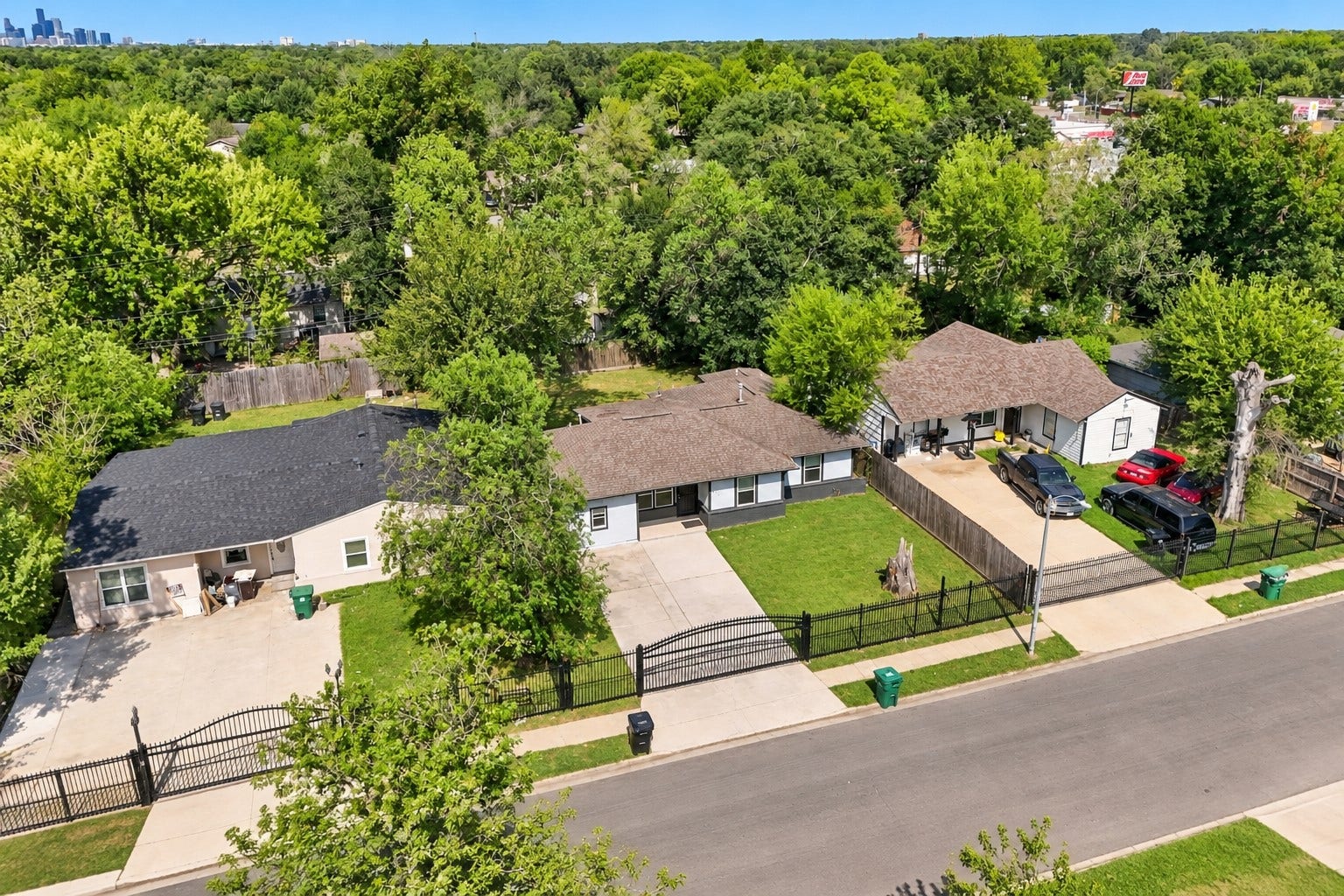 Take a look at this charming home from above! The aerial view showcases the single-story design, spacious driveway, front lawn, and fenced property, while the surrounding mature trees add a lovely touch of greenery to the setting.