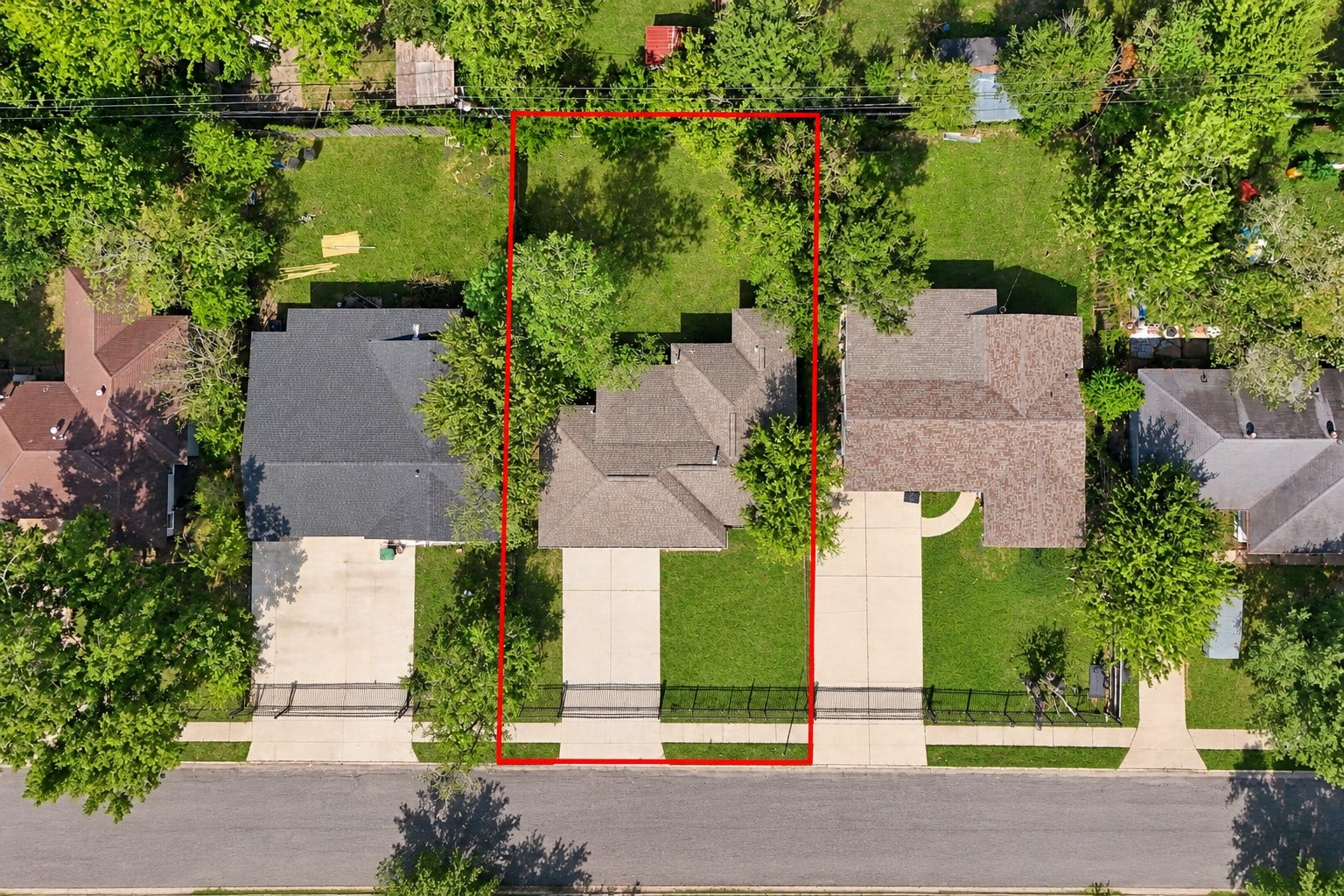 A fantastic overhead view highlighting the property's lot and layout! The aerial perspective clearly showcases the home, private driveway, fenced yard, and surrounding properties, giving you a better appreciation of the home's outdoor space and placement within the neighborhood.