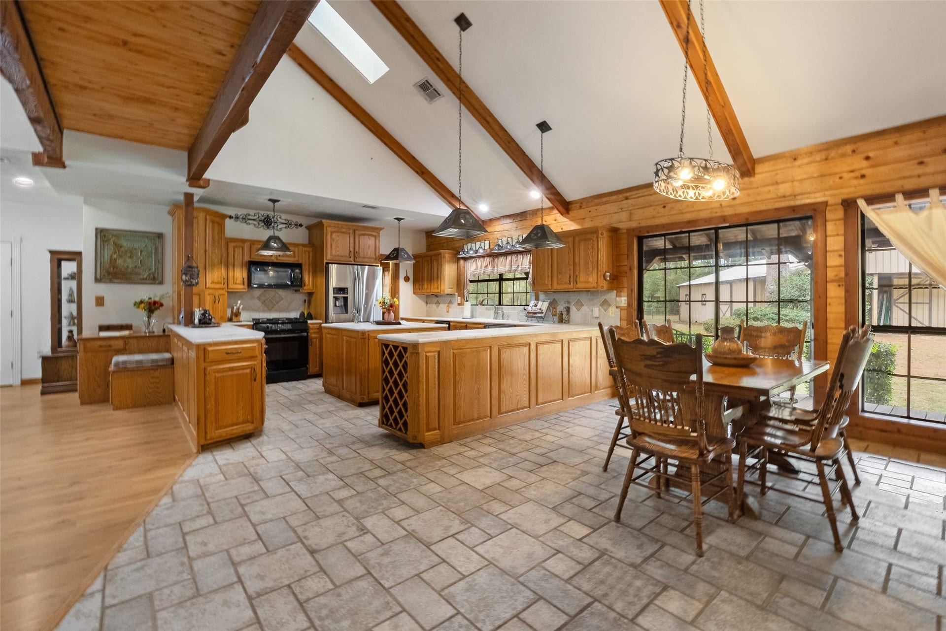 27874 Riley Road, Waller, TX 77484 Enjoy meals with a view in this charming dining area, where a vaulted ceiling, exposed wood beams and large windows bring together the warmth of cabin living and peaceful country scenery. A nearby door opens to the wraparound porch for easy access outdoors.