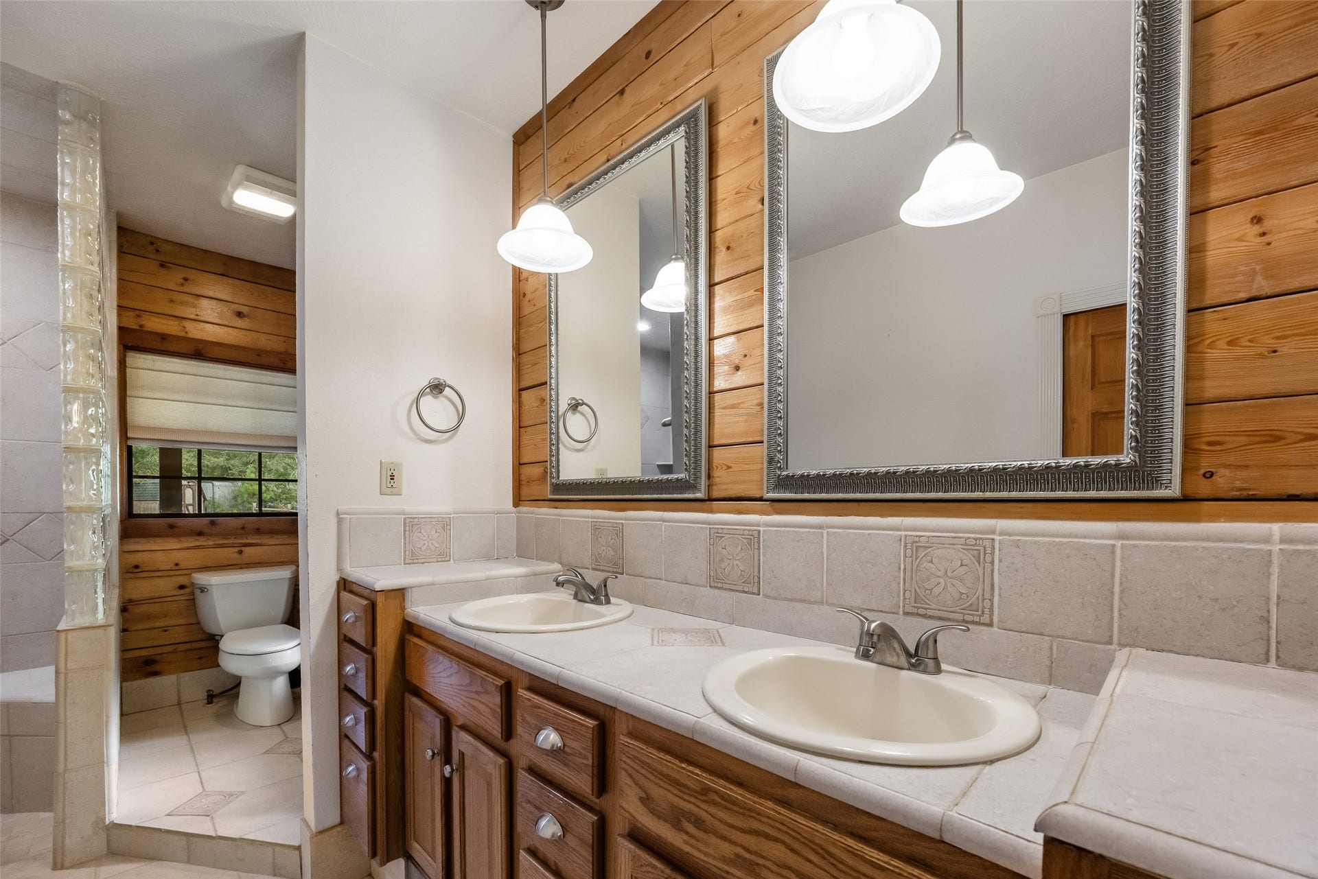 27874 Riley Road, Waller, TX 77484 The spacious primary ensuite features a long vanity with dual sinks, plenty of storage, decorative tile countertops and warm wood accents that add to the home's rustic charm.