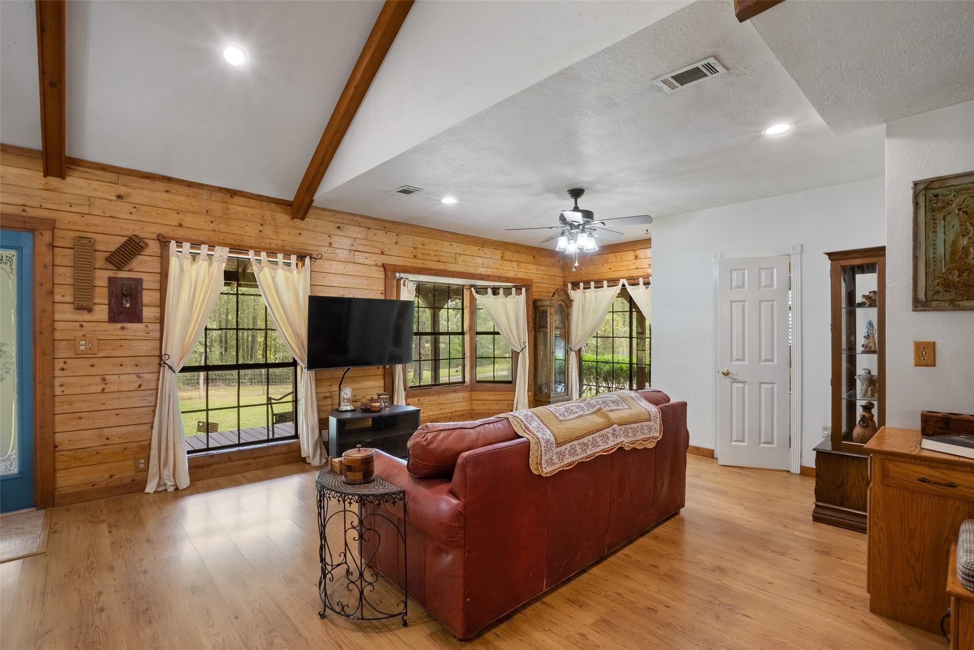 27874 Riley Road, Waller, TX 77484 Warm wood walls, exposed ceiling beams and beautiful wood-look flooring give this spacious family room its inviting cabin charm. Large windows bring in natural light and offer peaceful views of nature all around you.