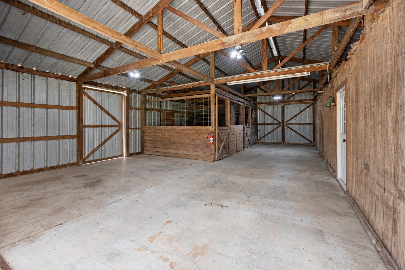 27874 Riley Road, Waller, TX 77484 The barn features two stalls with wood partitions, wire fencing and gates, offering a practical setup for horses or other livestock, with plenty of additional room for equipment and storage.