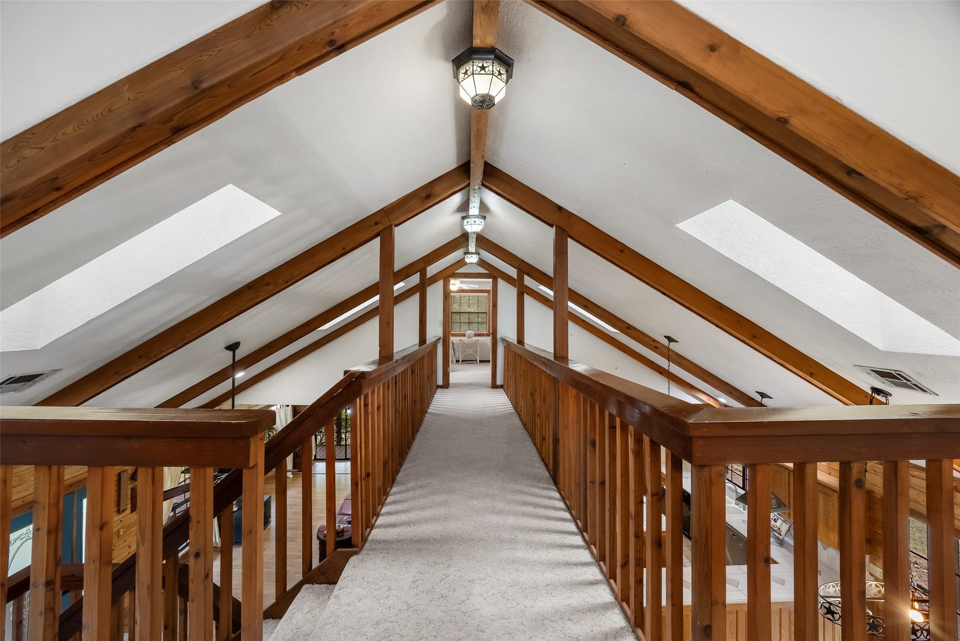 27874 Riley Road, Waller, TX 77484 A beautiful vaulted ceiling with exposed wood beams, skylights and decorative lighting creates a dramatic view along the upstairs walkway. Open railings overlook the living and dining areas below, adding to the home's rustic charm and spacious feel.