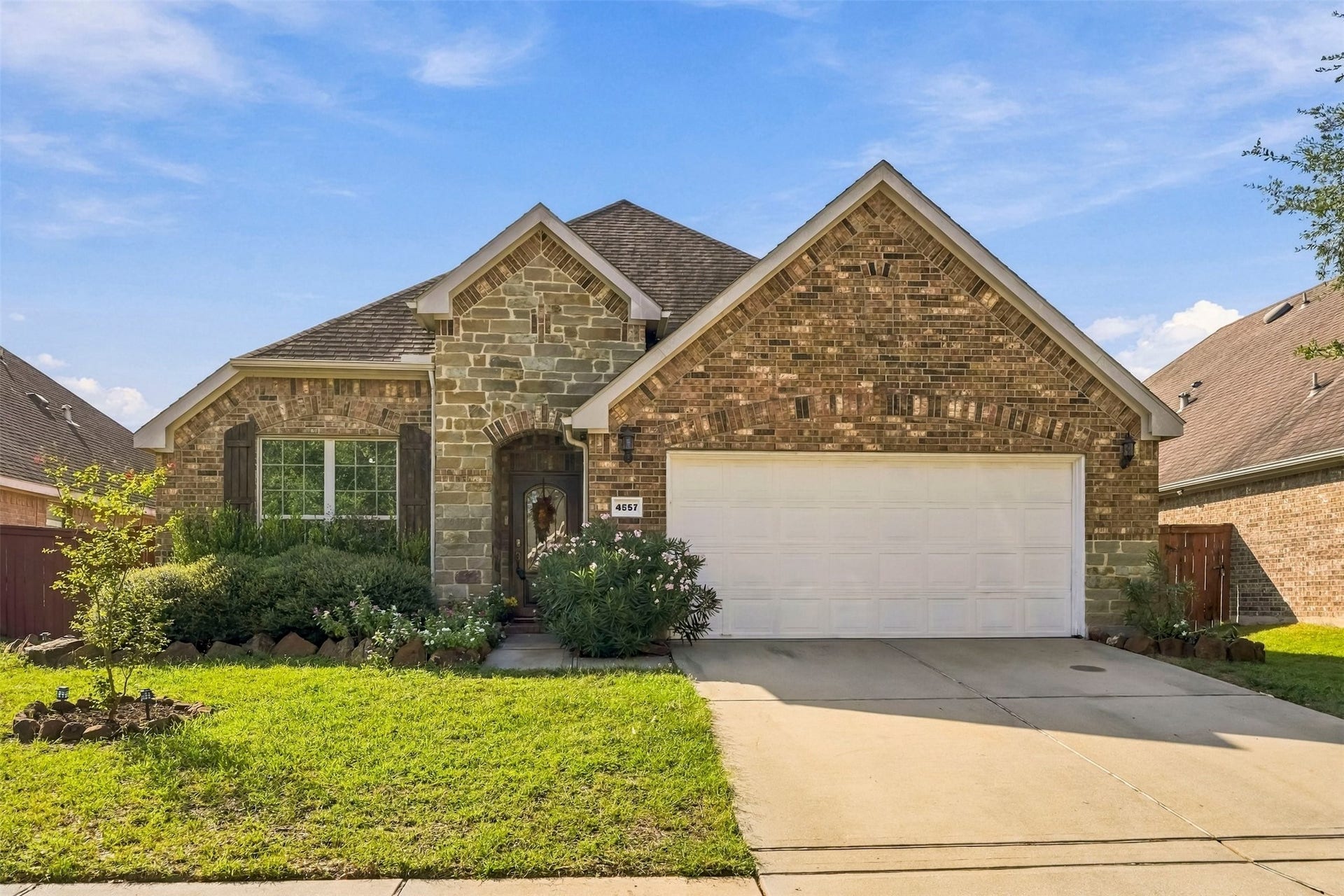 4557 Argonne Woods Drive, Porter, TX 77365 Charming single-story home with a stone and brick facade, featuring a spacious two-car garage and well-maintained landscaping.