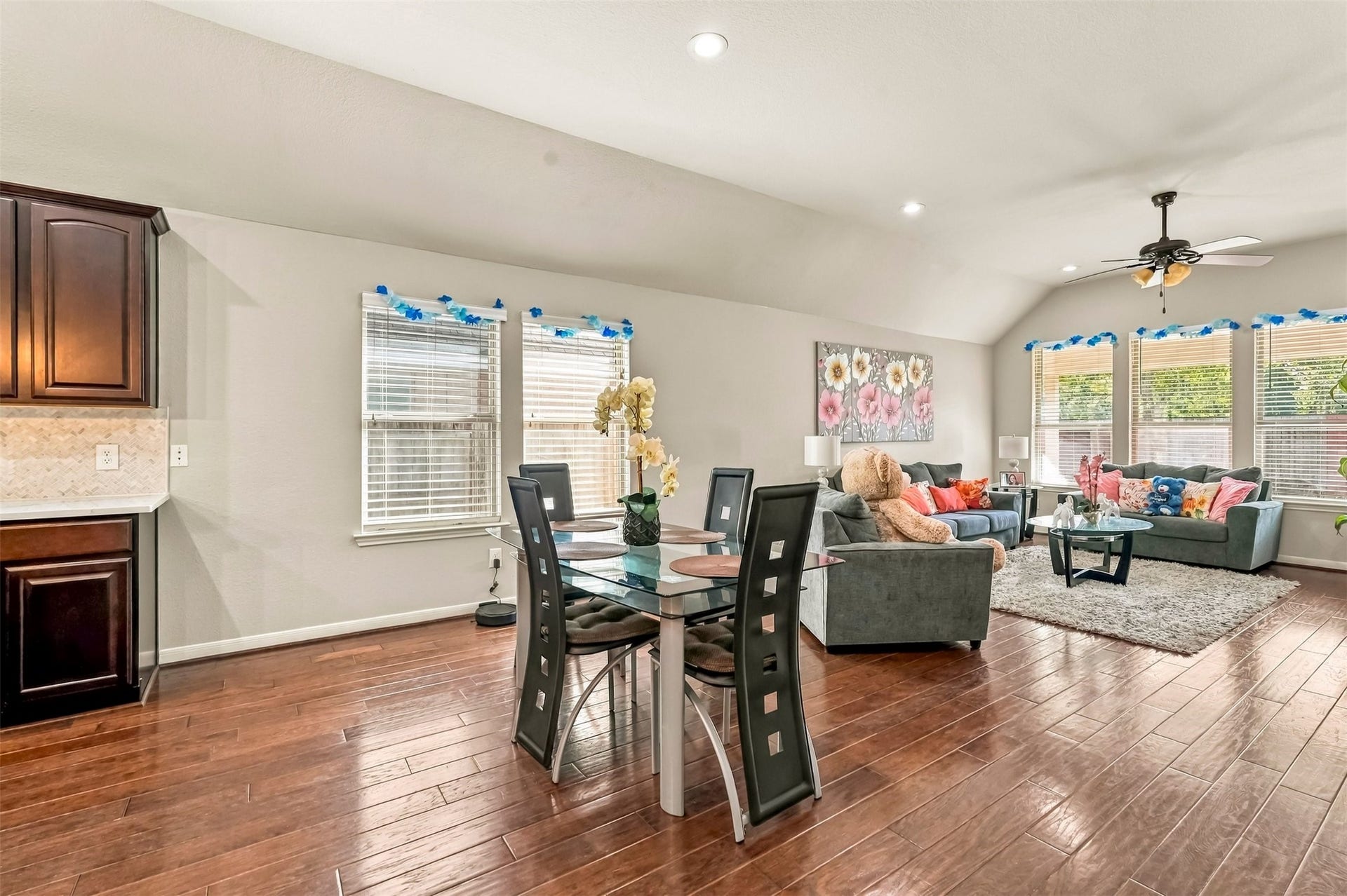 4557 Argonne Woods Drive, Porter, TX 77365 Spacious open-concept living and dining area with elegant hardwood floors, abundant natural light from large windows, and a cozy seating arrangement perfect for relaxing or entertaining.