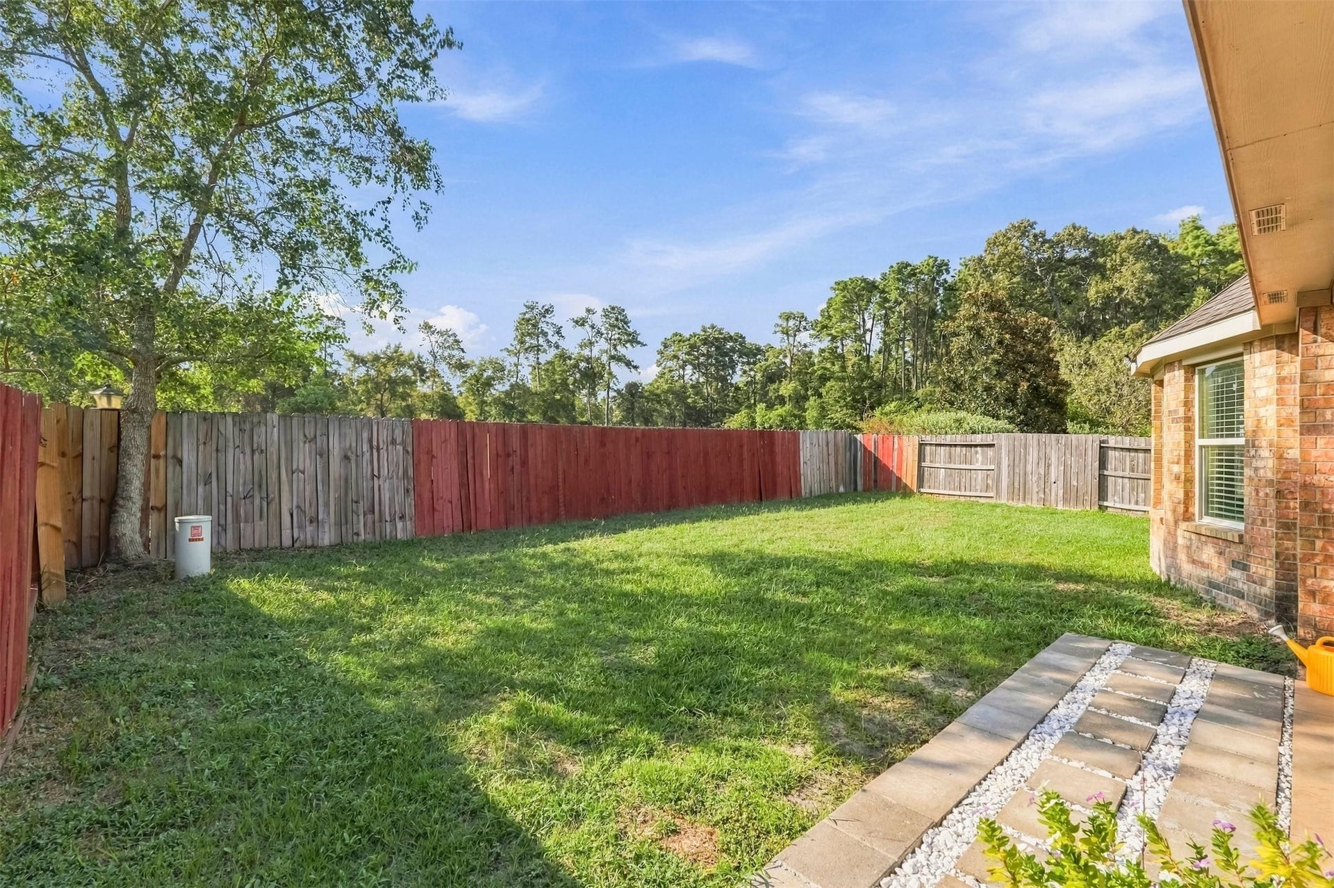 4557 Argonne Woods Drive, Porter, TX 77365 Spacious backyard with lush green grass, bordered by a charming wooden fence, perfect for outdoor activities and relaxation.