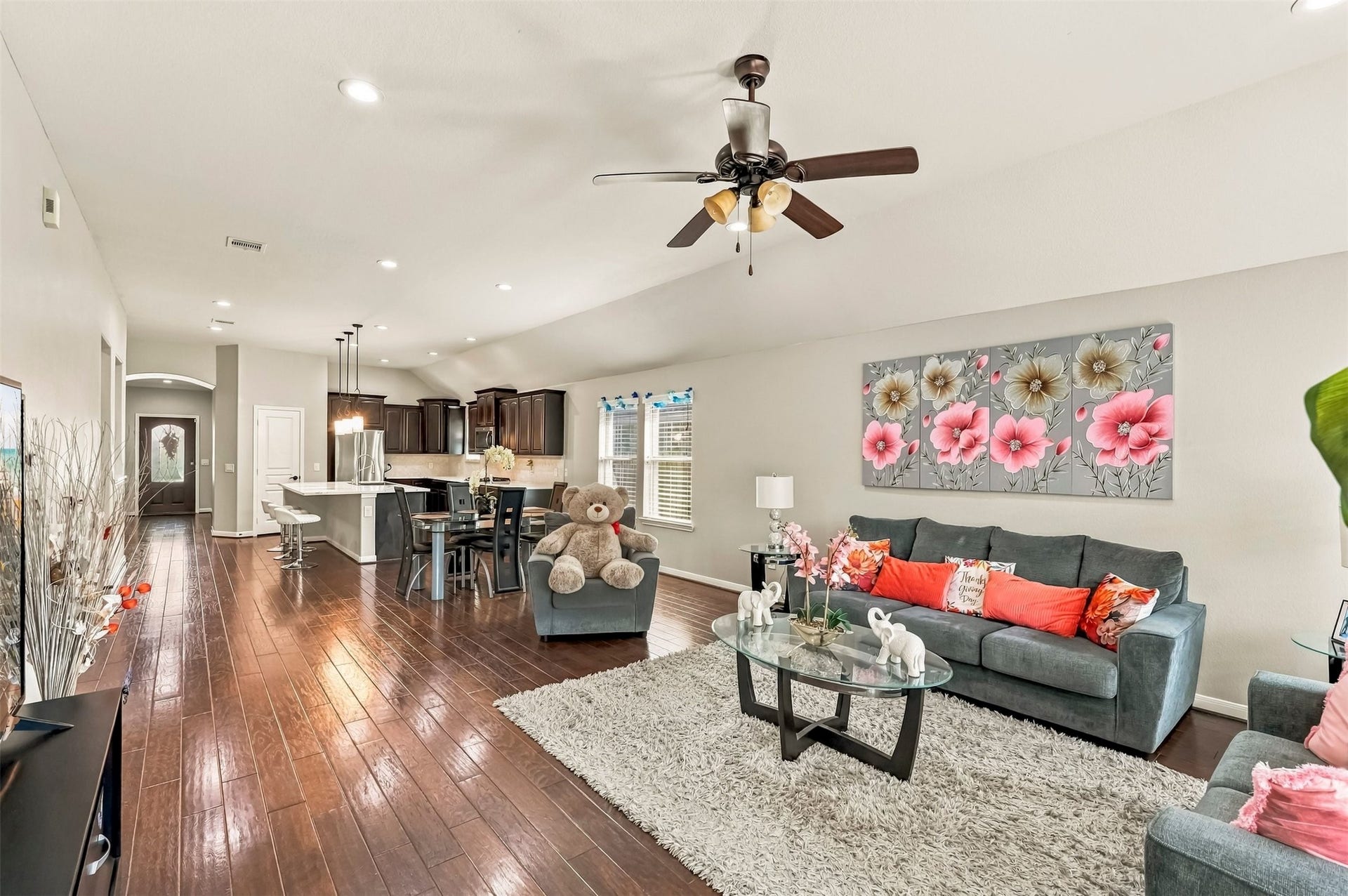4557 Argonne Woods Drive, Porter, TX 77365 Spacious open-concept living area featuring elegant hardwood floors, a cozy seating arrangement, and a modern kitchen with dark cabinetry and a breakfast bar, perfect for entertaining.