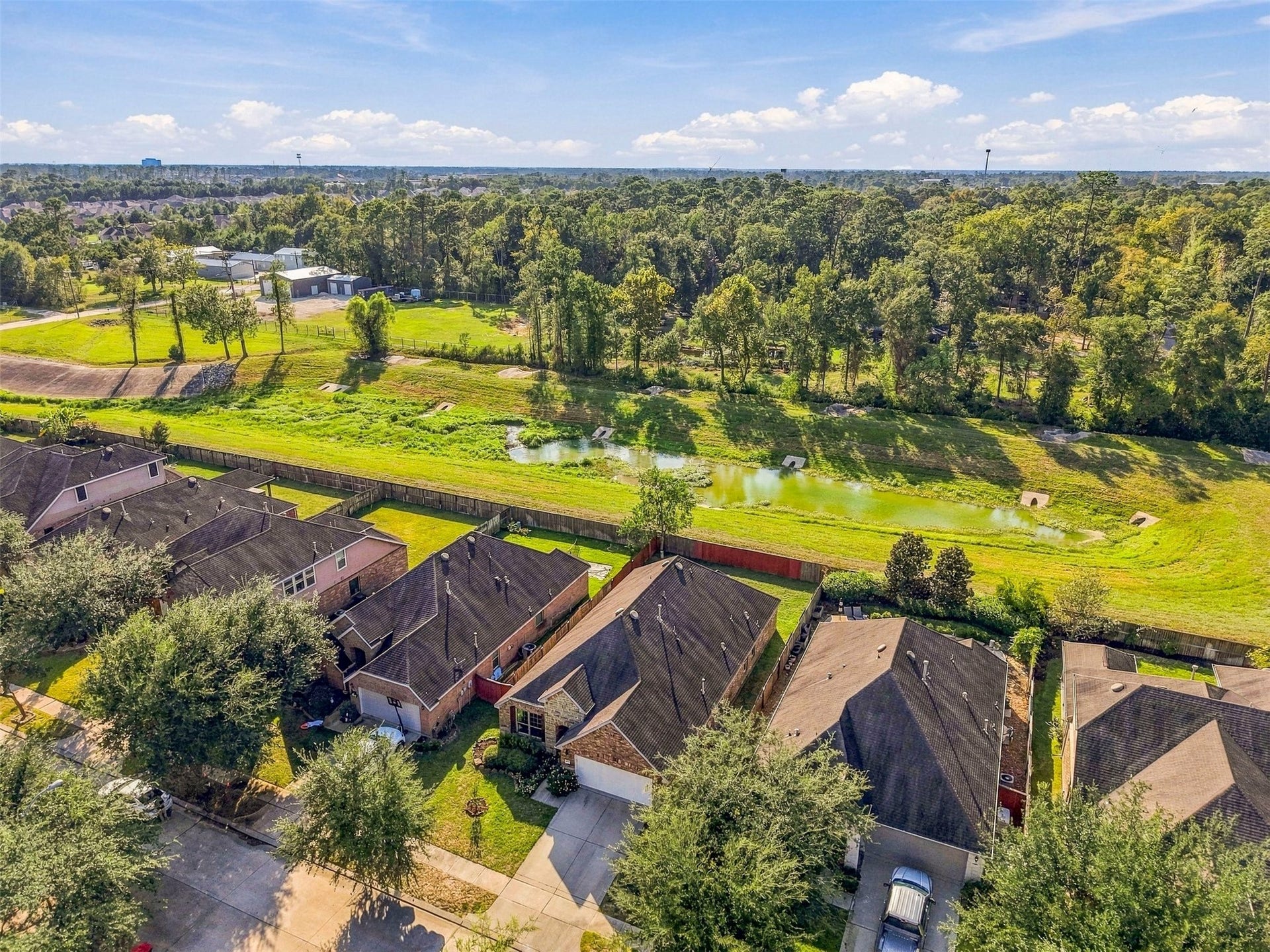 4557 Argonne Woods Drive, Porter, TX 77365 Charming neighborhood with lush greenery and a serene pond view, offering a peaceful retreat near natural surroundings.