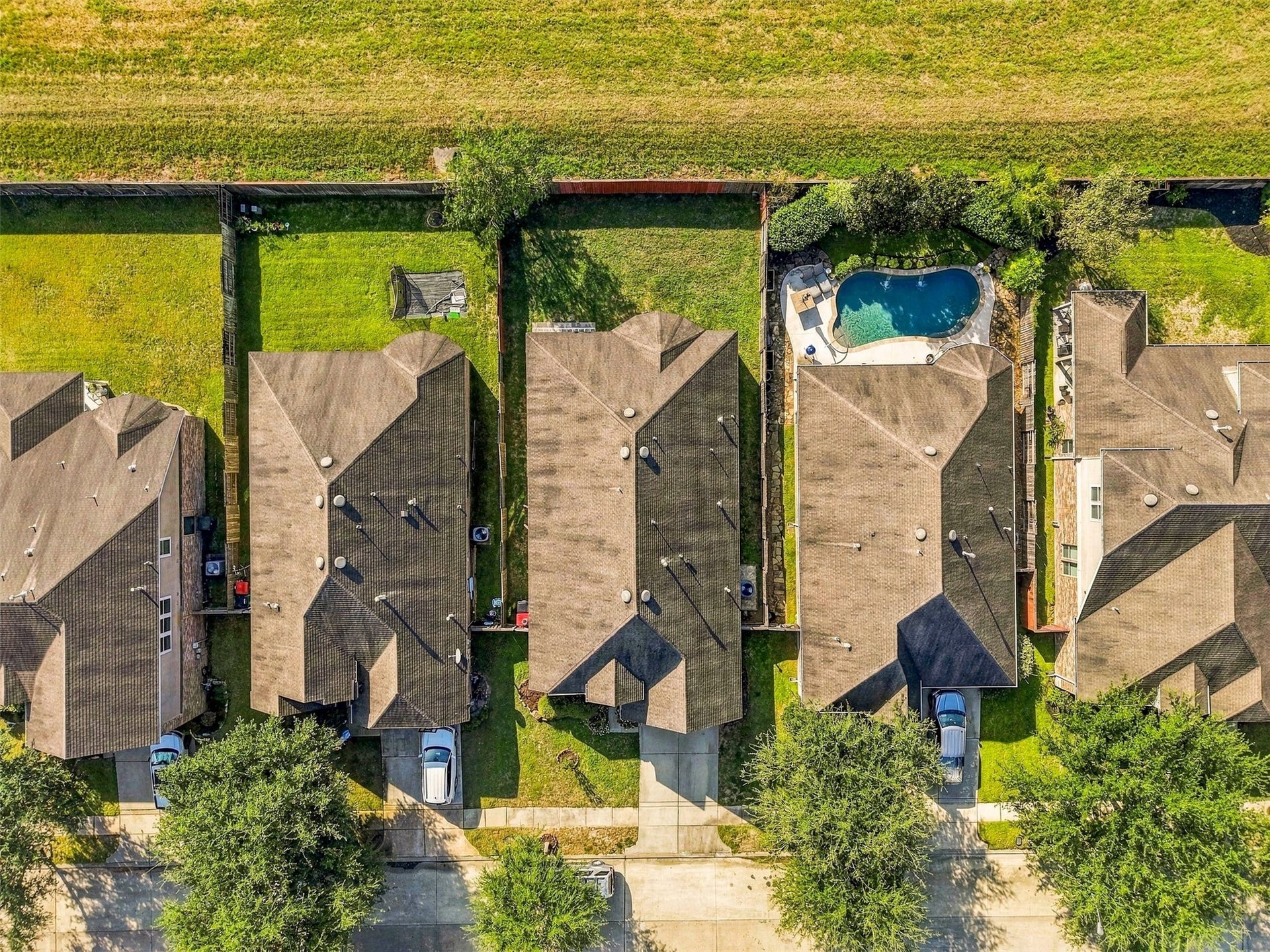 4557 Argonne Woods Drive, Porter, TX 77365 Aerial view of a suburban neighborhood showcasing neatly aligned homes with spacious yards, one featuring a private swimming pool, all surrounded by lush greenery.