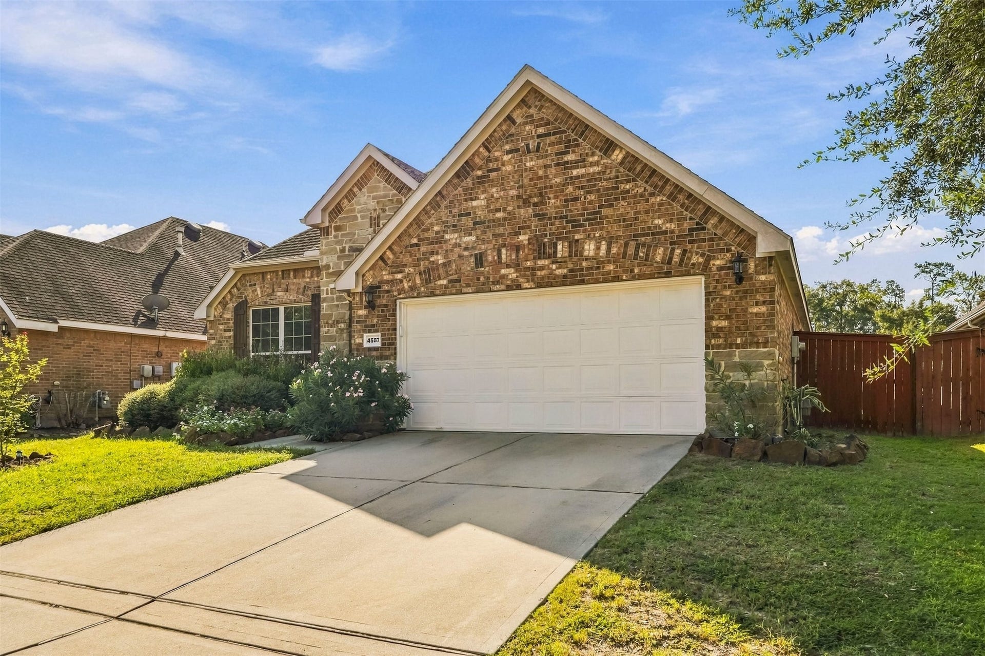 4557 Argonne Woods Drive, Porter, TX 77365 Charming brick home with a spacious two-car garage, welcoming front garden, and a neatly manicured lawn, offering great curb appeal.