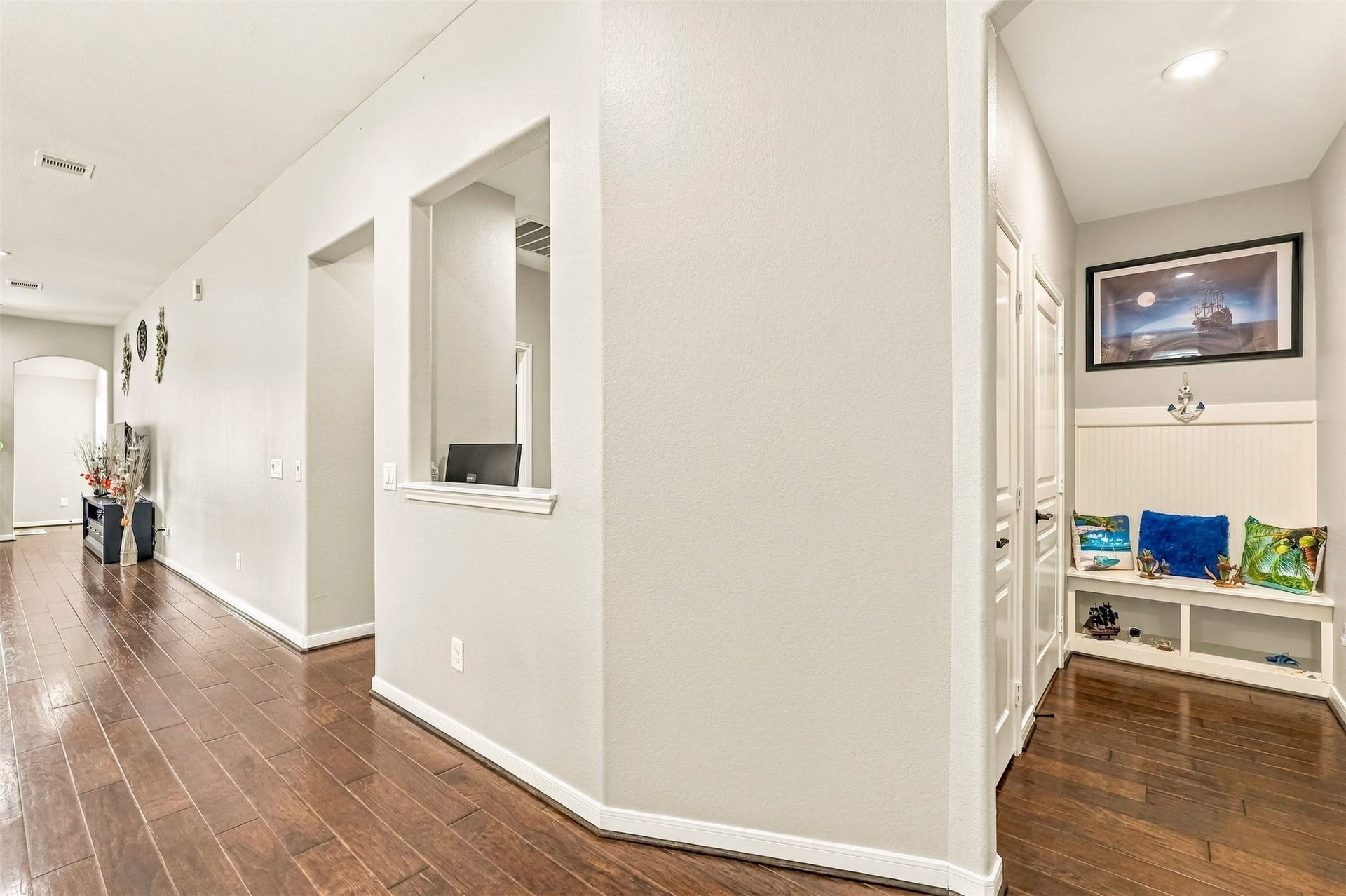 4557 Argonne Woods Drive, Porter, TX 77365 Inviting hallway with elegant dark wood flooring, white walls, and a cozy nook featuring built-in seating and artistic decor.