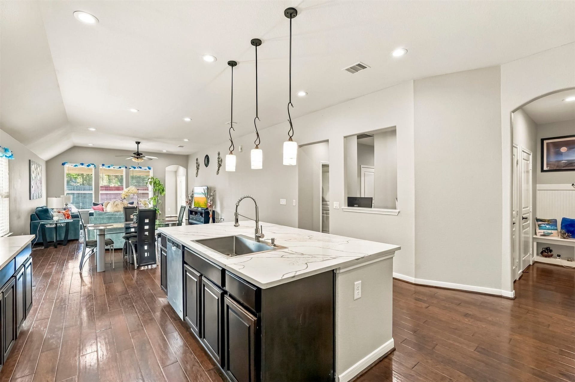 4557 Argonne Woods Drive, Porter, TX 77365 Spacious open-concept kitchen and living area featuring elegant pendant lighting, sleek countertops, and rich wood flooring, seamlessly flowing into a cozy dining space with abundant natural light.