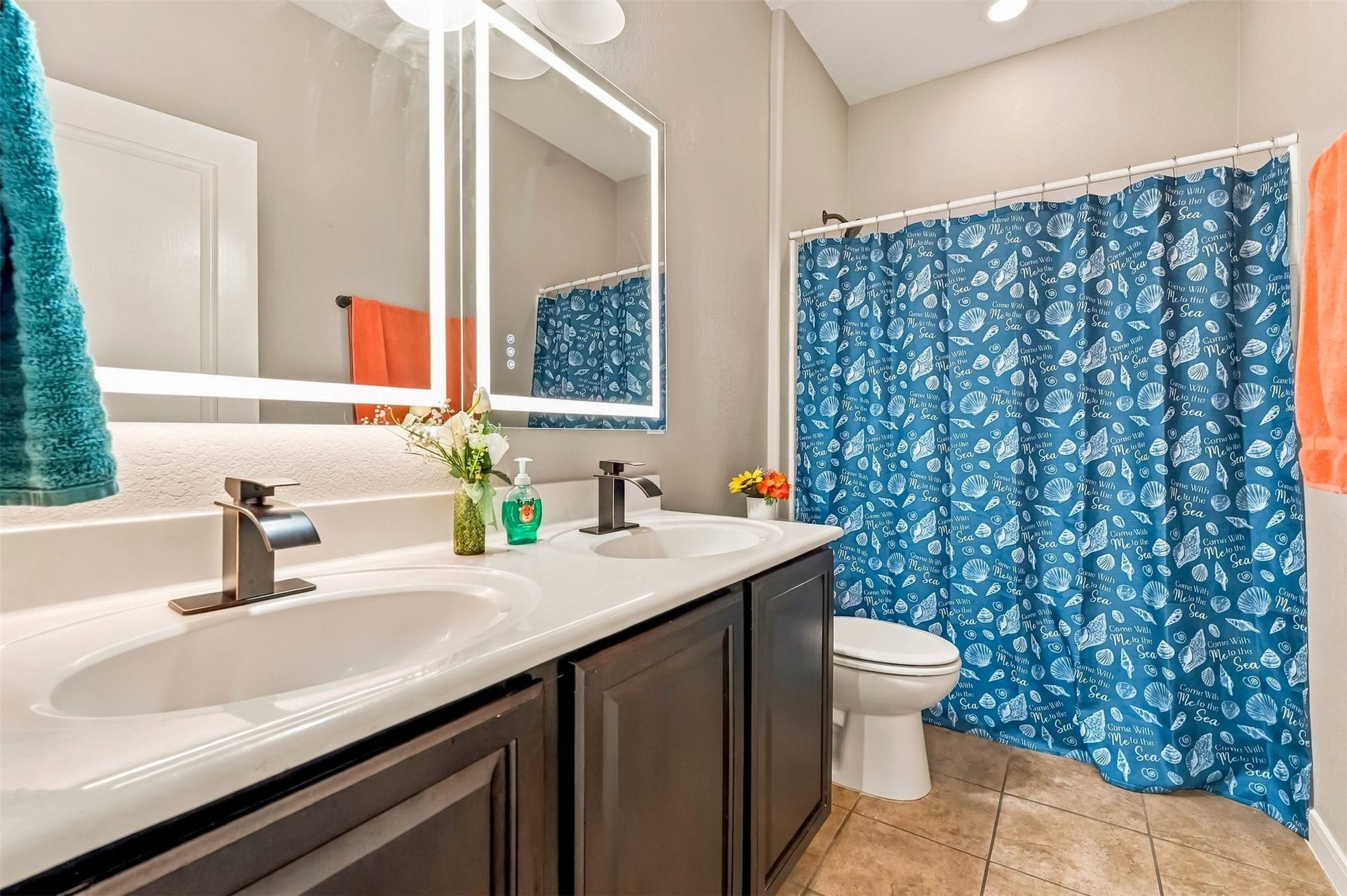 4557 Argonne Woods Drive, Porter, TX 77365 Bright and inviting bathroom featuring a double vanity with sleek fixtures, a large mirror, and a vibrant blue shower curtain, offering both style and functionality.