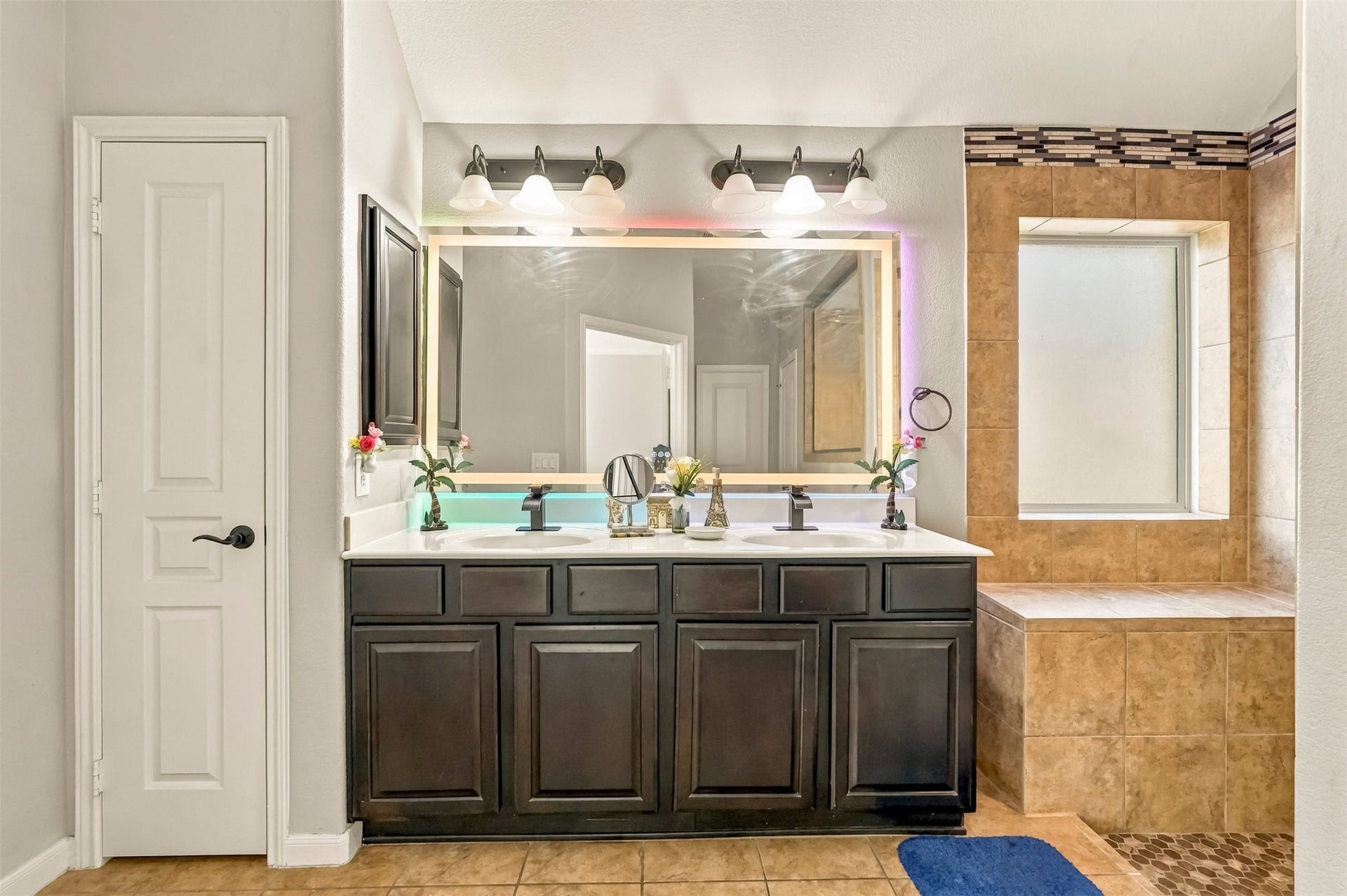 4557 Argonne Woods Drive, Porter, TX 77365 Elegant bathroom with a dual-sink vanity, stylish dark cabinetry, and modern lighting. Adjacent is a spacious tiled shower area with a large window for natural light.
