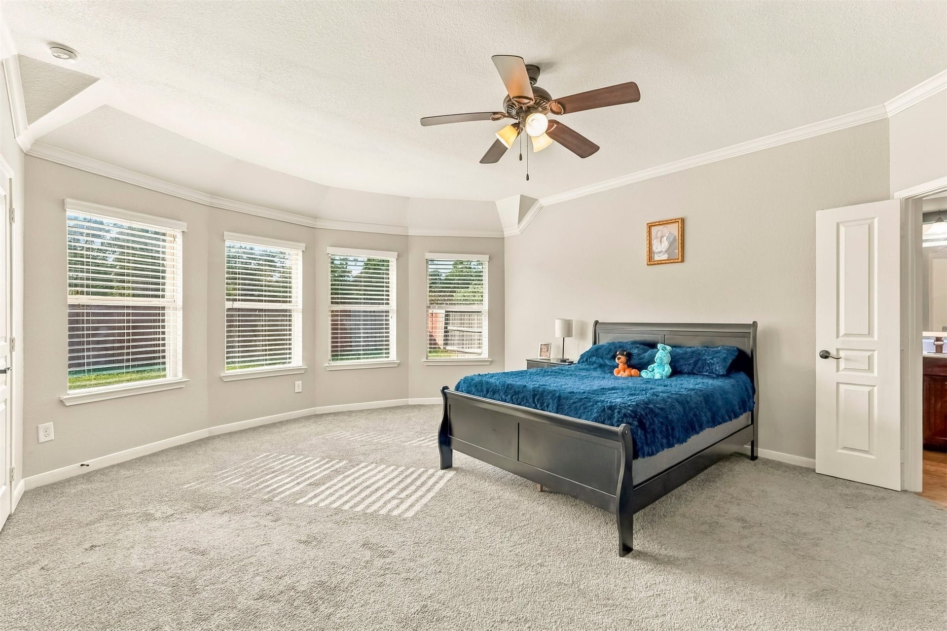4557 Argonne Woods Drive, Porter, TX 77365 Spacious bedroom with abundant natural light from large bay windows, featuring a cozy carpet and elegant ceiling fan.