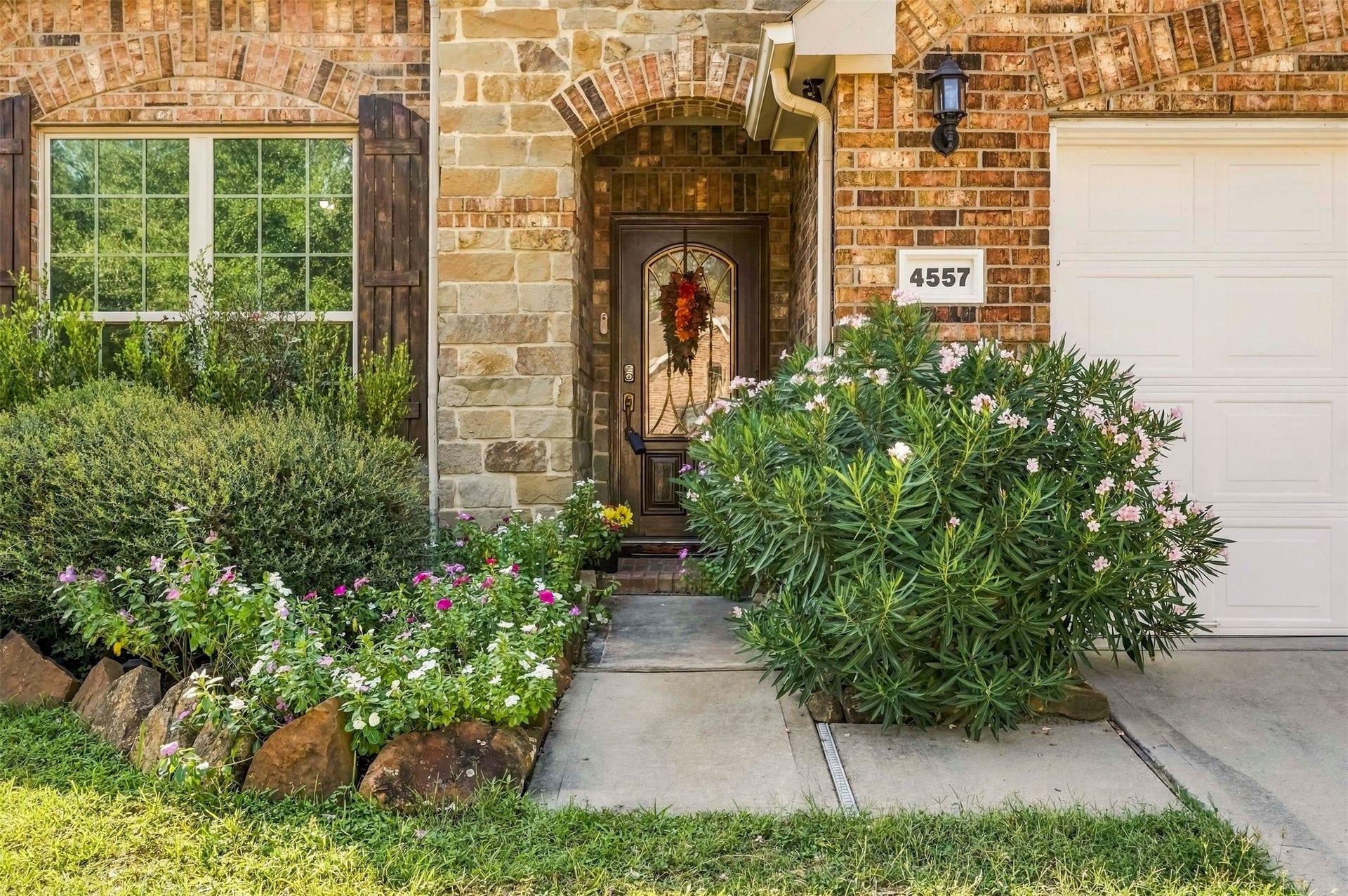 4557 Argonne Woods Drive, Porter, TX 77365 Charming brick and stone facade with lush landscaping and a welcoming front door, perfect for a cozy entryway.