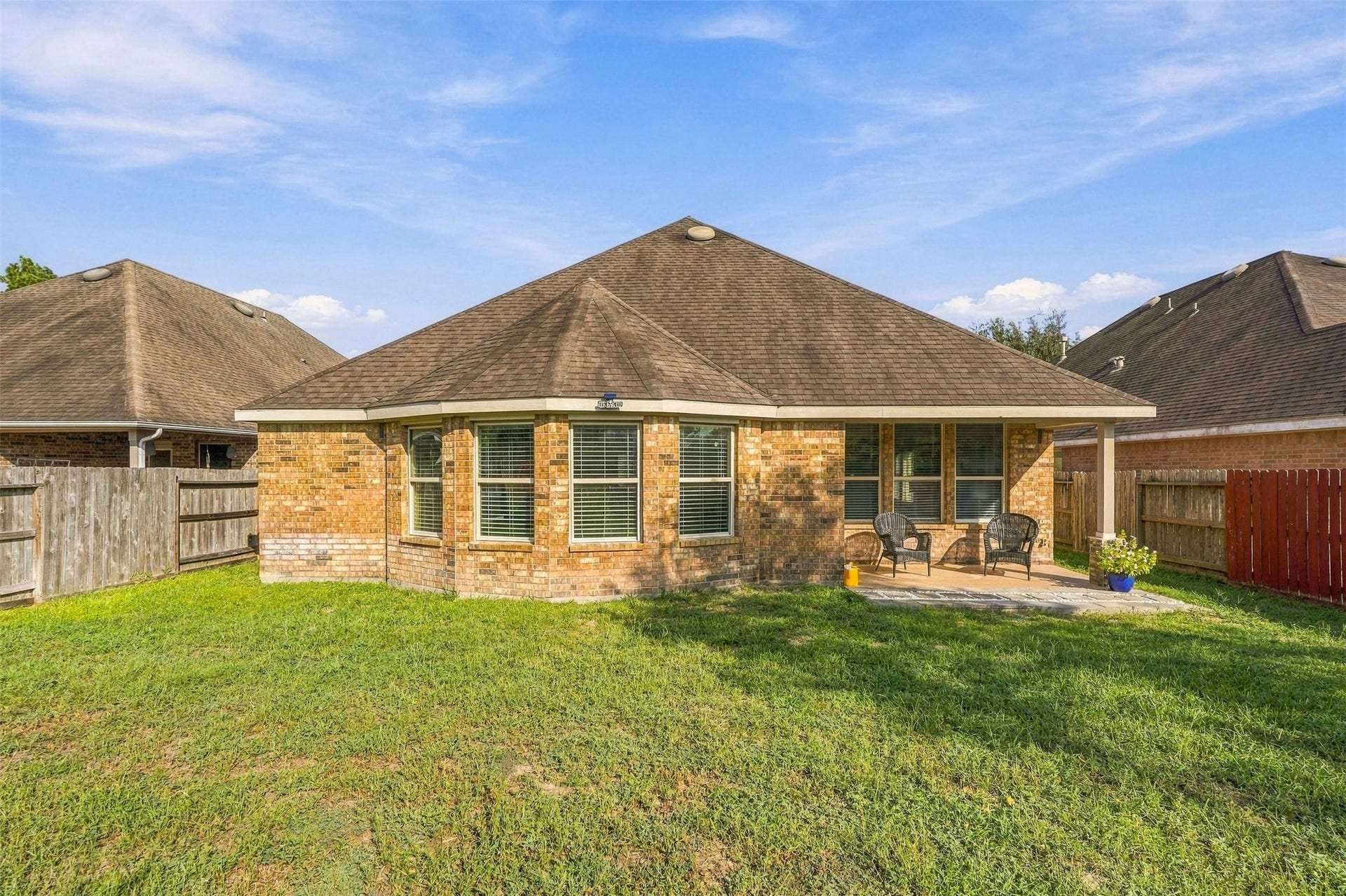 4557 Argonne Woods Drive, Porter, TX 77365 Charming brick home with a spacious backyard, featuring a cozy patio area perfect for outdoor relaxation and entertainment.