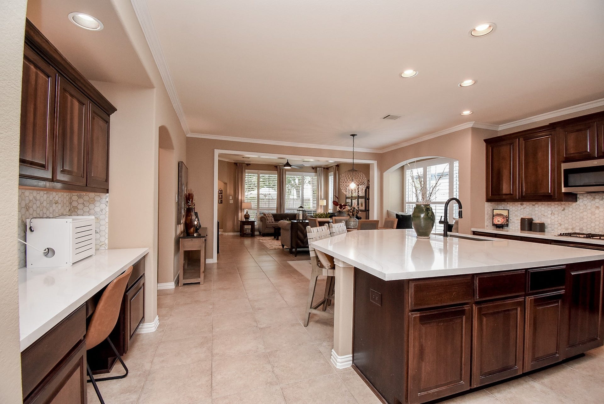 Kitchen with extra desk space has matching tile backsplash, countertops and lots of storage.