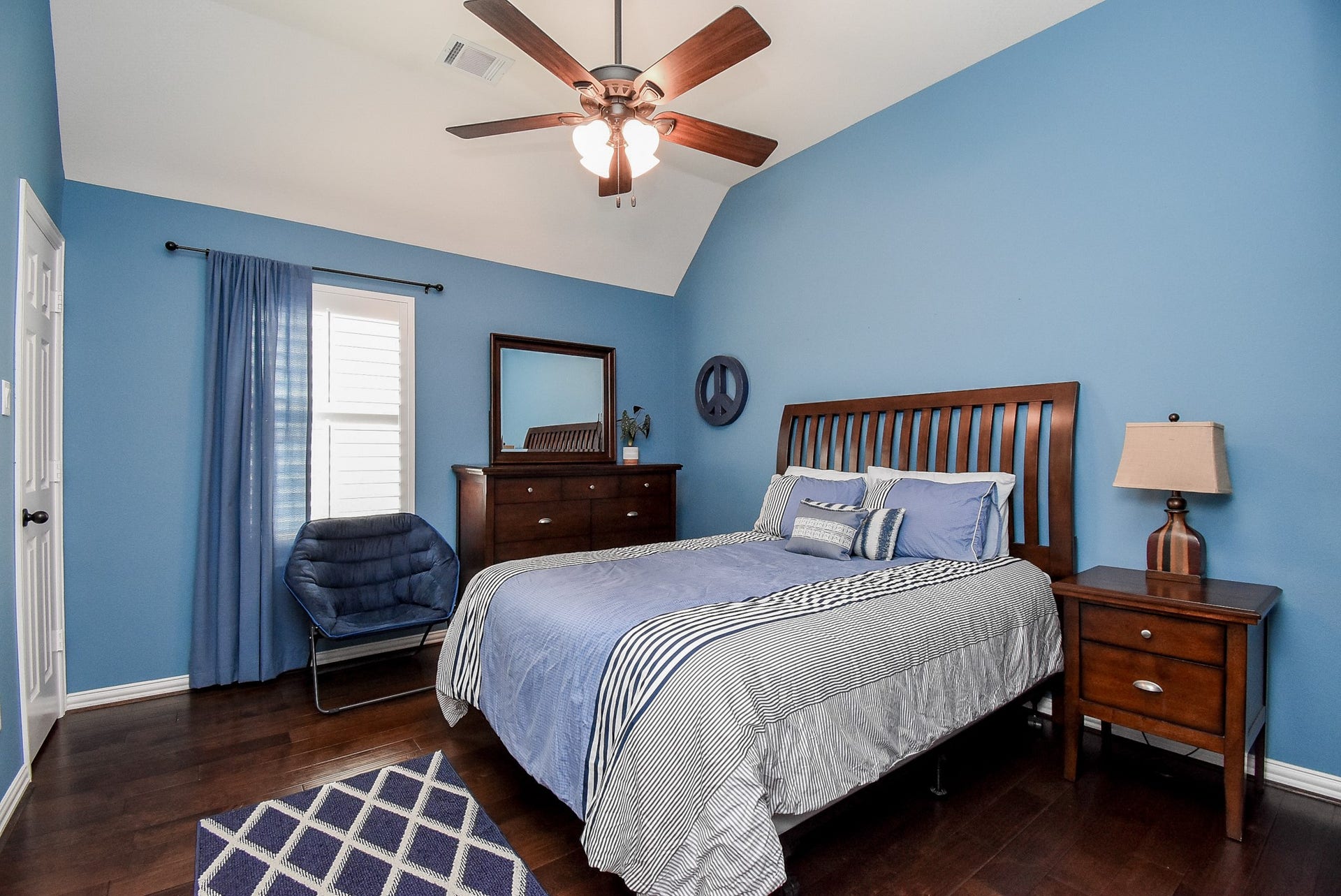 Secondary upstairs bedroom with ceiling fan and wood flooring.