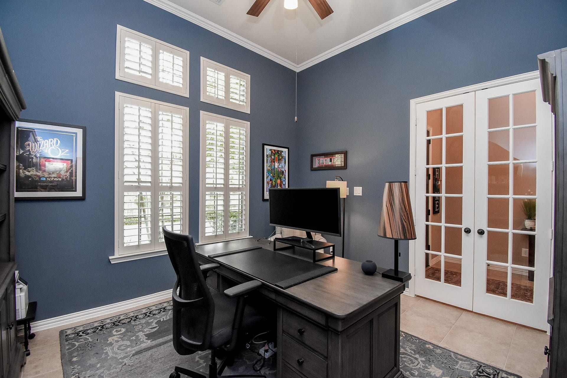 Large study with lots of natural light, shutters and ceiling fan.