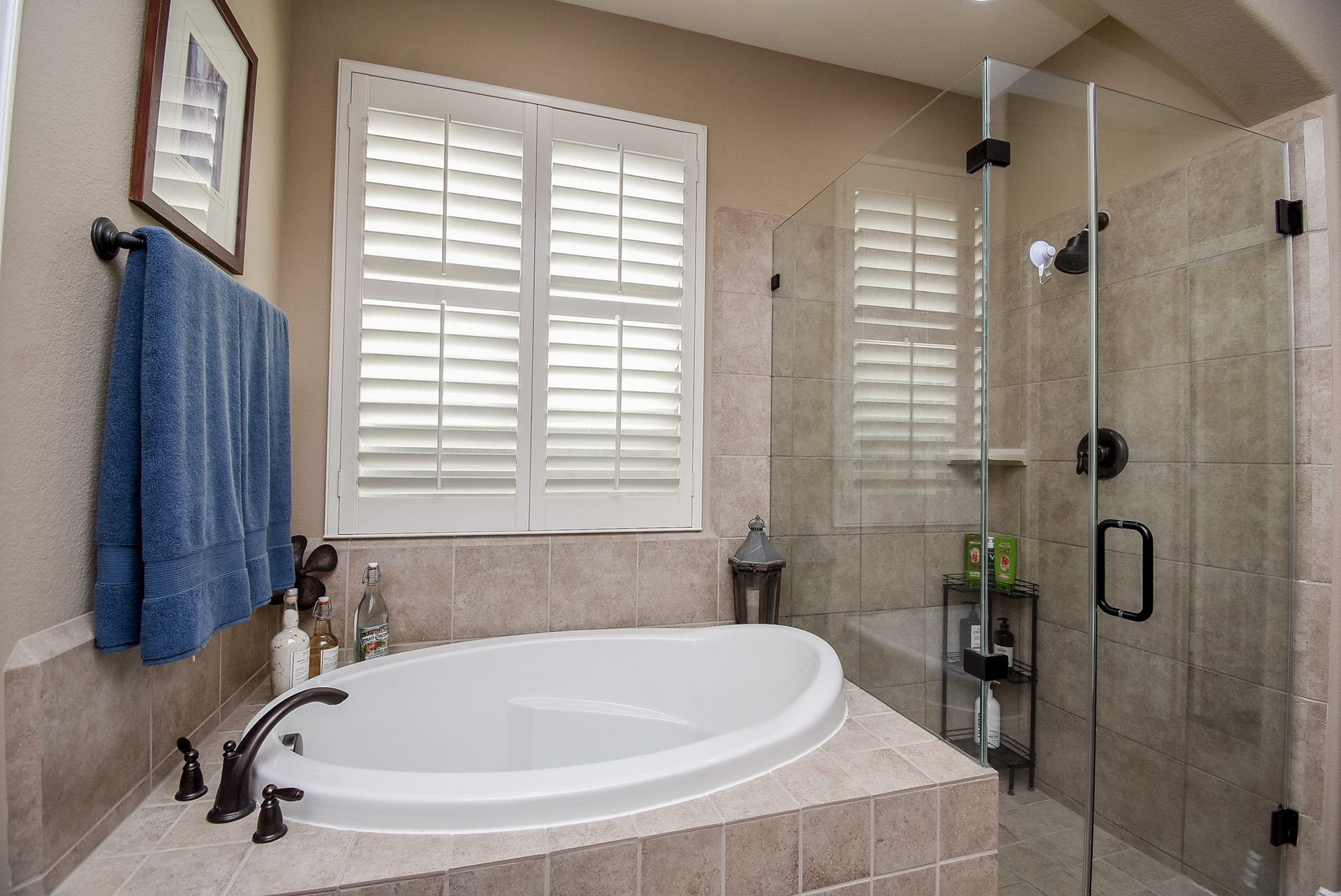Soaking tub with large walk in glass shower, wood shutters.