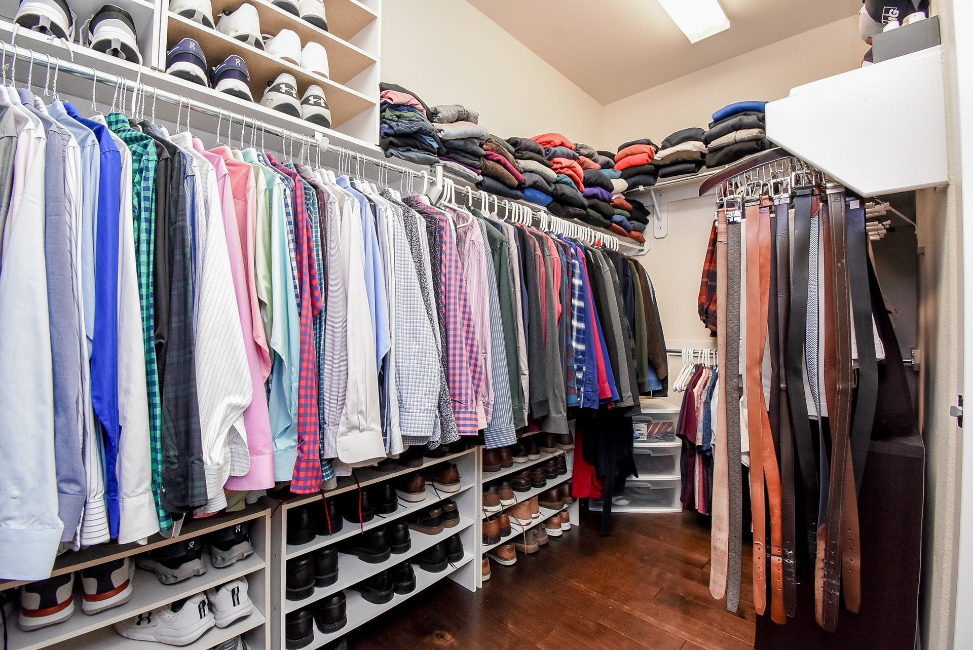Primary walk in closet with wood flooring, has plenty of hanging and storage.