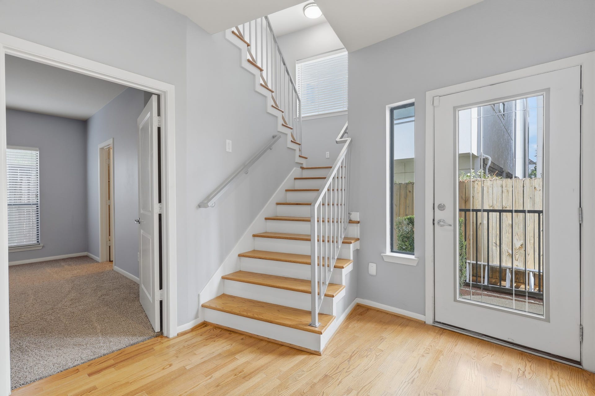 The bright, well lit stairway illuminated by natural light just beyond the front entry, offers an inviting first glimpse of the refinished hardwood floors.