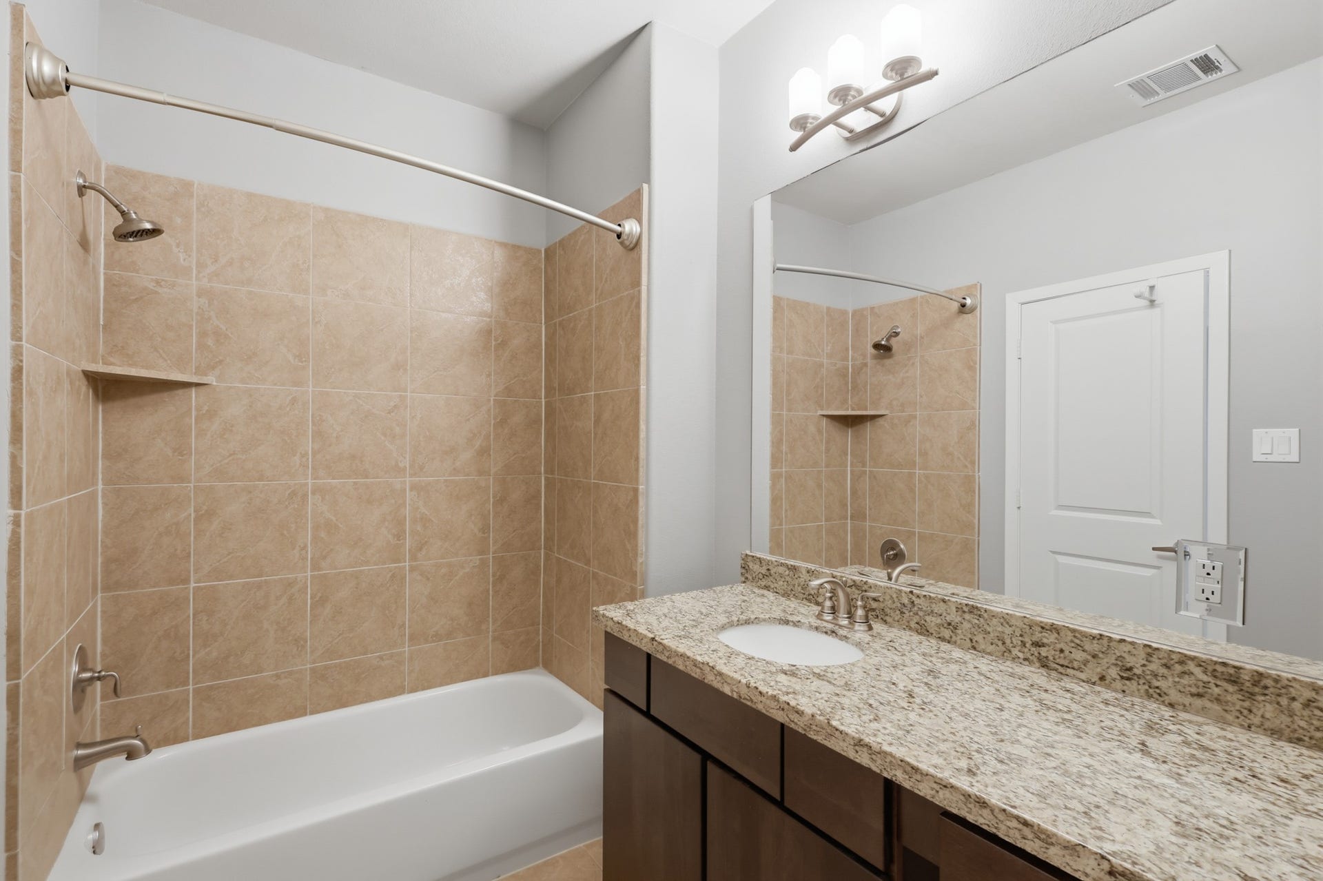 First floor en suite bathroom featuring a wood cabinetry vanity with granite countertops and a combination tub and shower.