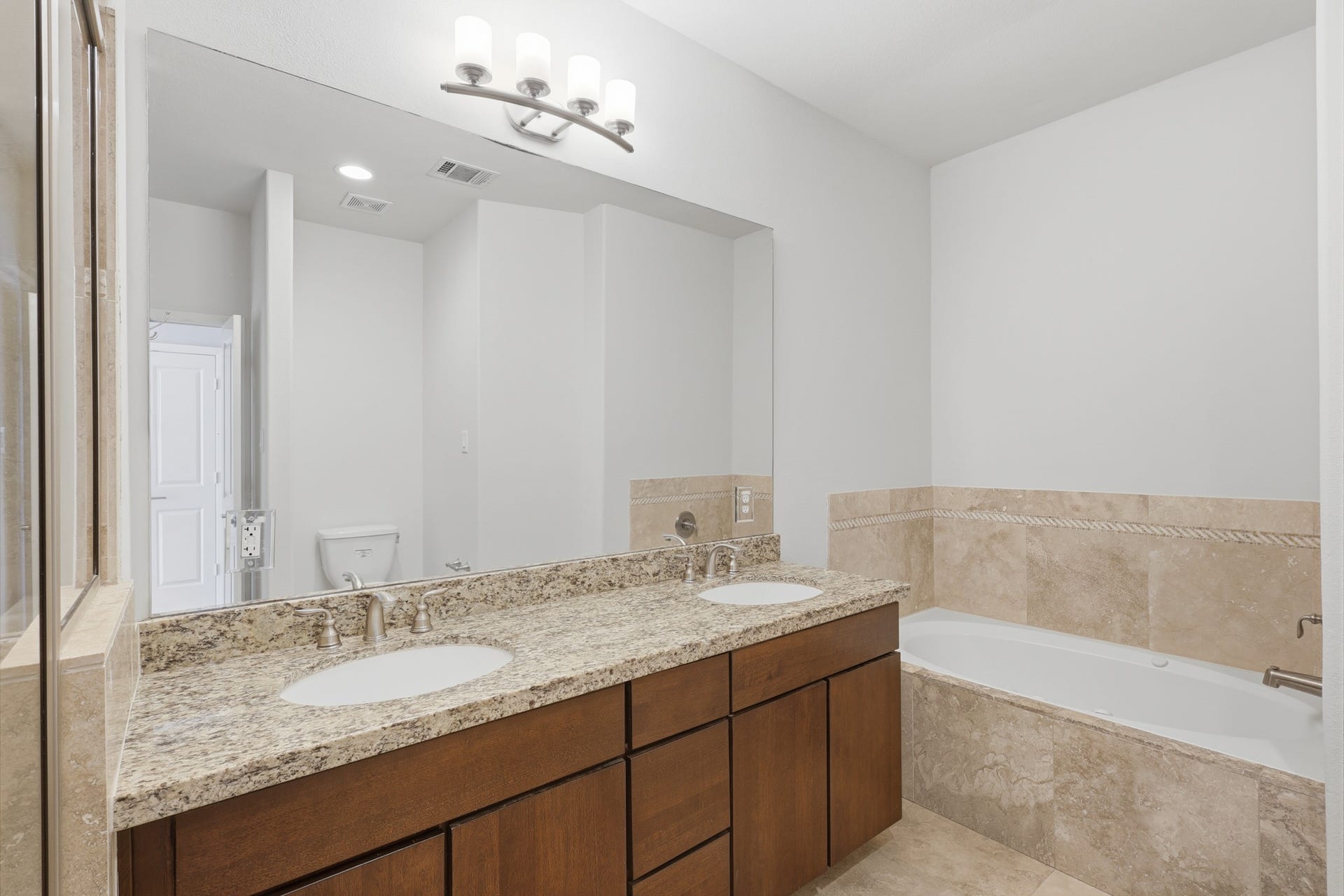 Primary en suite bathroom featuring dual vanities, generous counter space, a soaking tub, and separate shower.