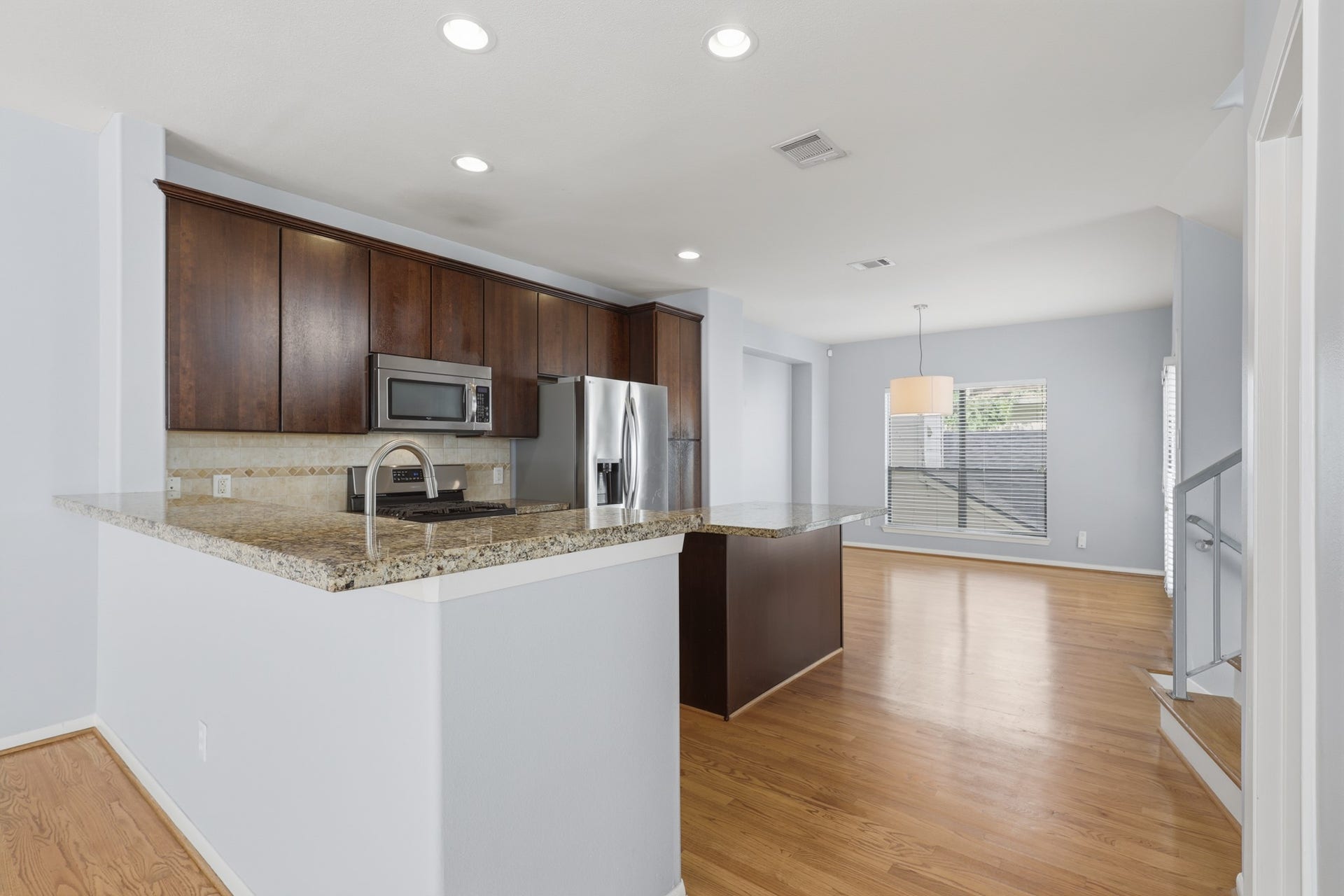 The kitchen features wood cabinetry, granite countertops, and stainless steel appliances, with both a breakfast bar and a freestanding island