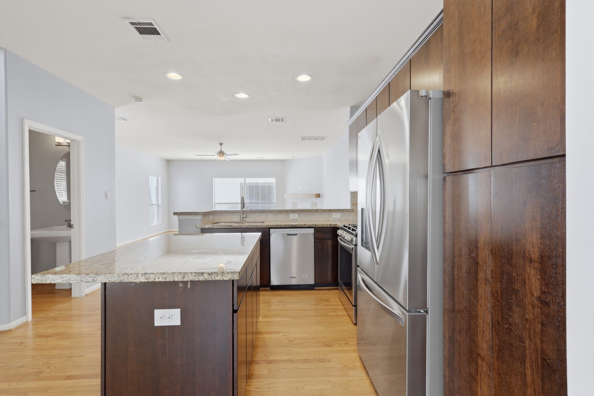 Living area in background showcases the open connection to the kitchen and dining spaces, with a glimpse of the conveniently located powder room.