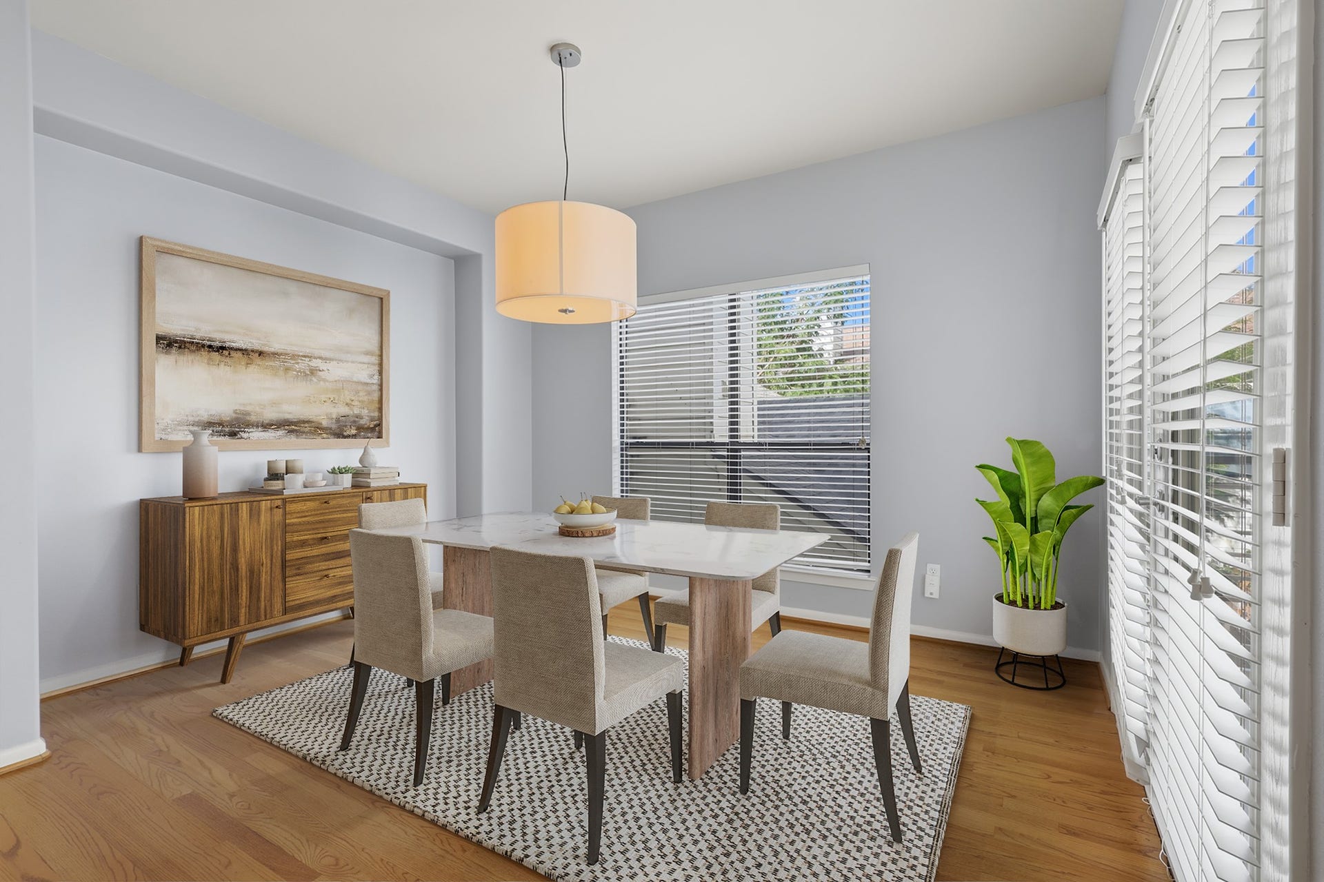 The virtually staged dining area fills with natural light through a large window in the background and double doors that bring additional brightness into the space.