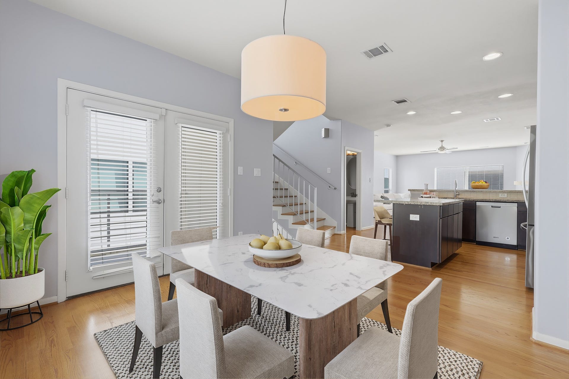 Virtually staged dining area shows a clear view of the kitchen in the background, highlighting the open flow between the main living spaces.