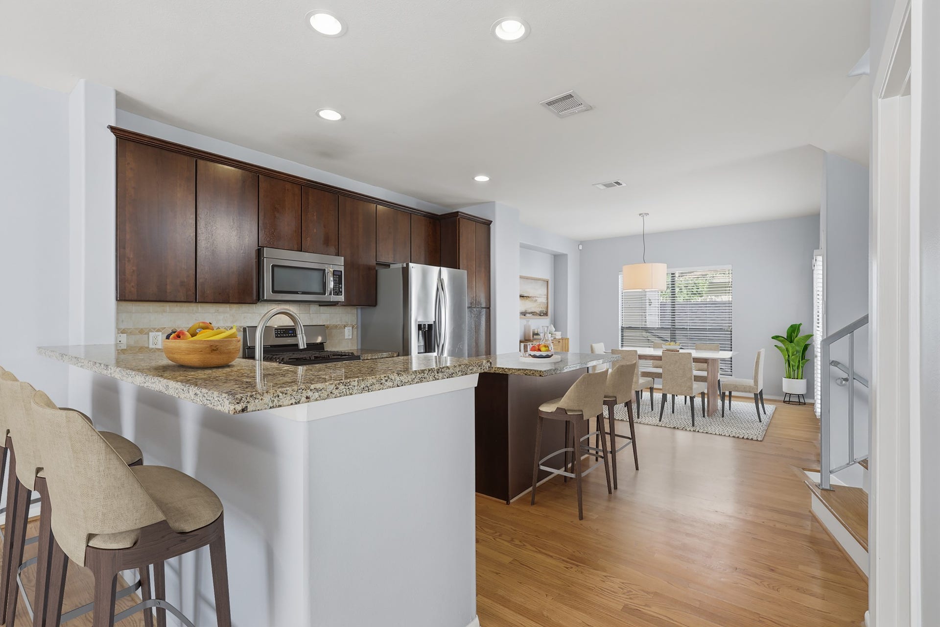 Virtually staged kitchen featuring wood cabinetry and refinished hardwood floors, with a dedicated dining area visible in the background.