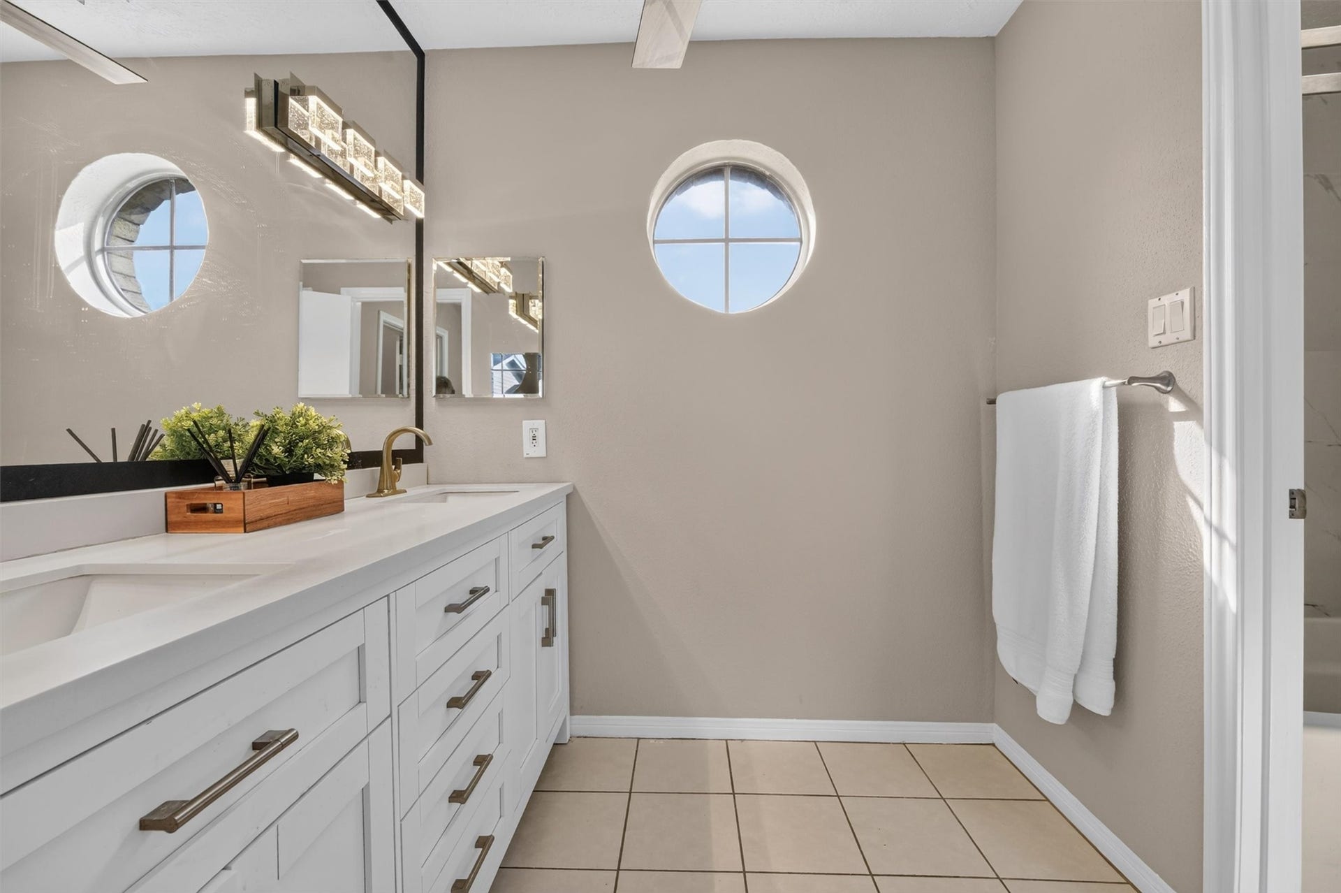 2220 Bering Drive, #12, Houston, TX 77057 Primary bathroom with a double-sink vanity, generous cabinet storage, and distinctive round windows.