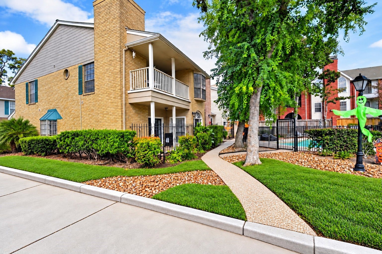 2220 Bering Drive, #12, Houston, TX 77057 Inviting exterior with a covered balcony, mature trees, and landscaped grounds beside the community pool.