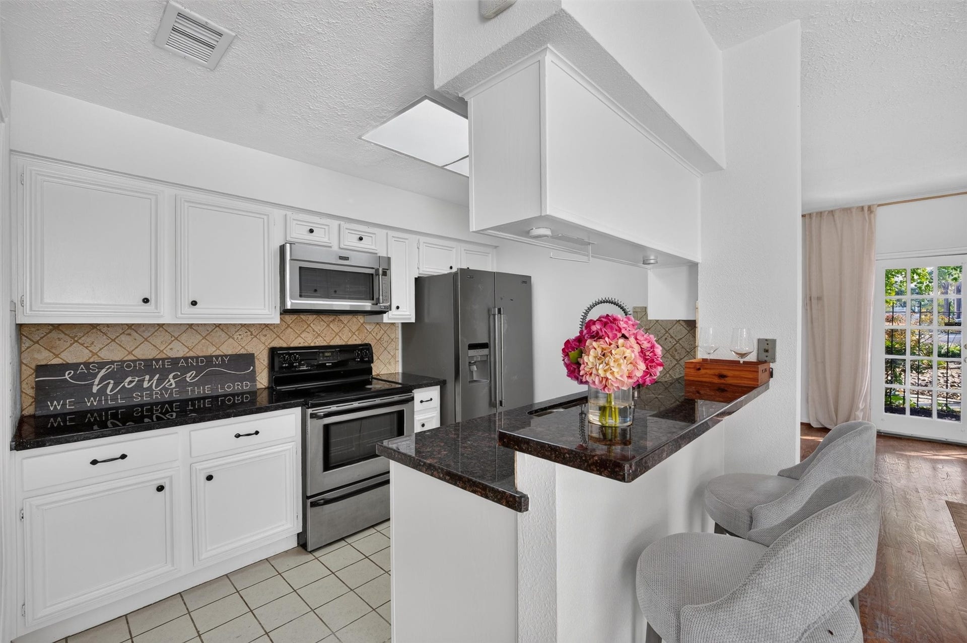 2220 Bering Drive, #12, Houston, TX 77057 Kitchen featuring white cabinetry, dark countertops, stainless steel appliances, and breakfast bar seating.