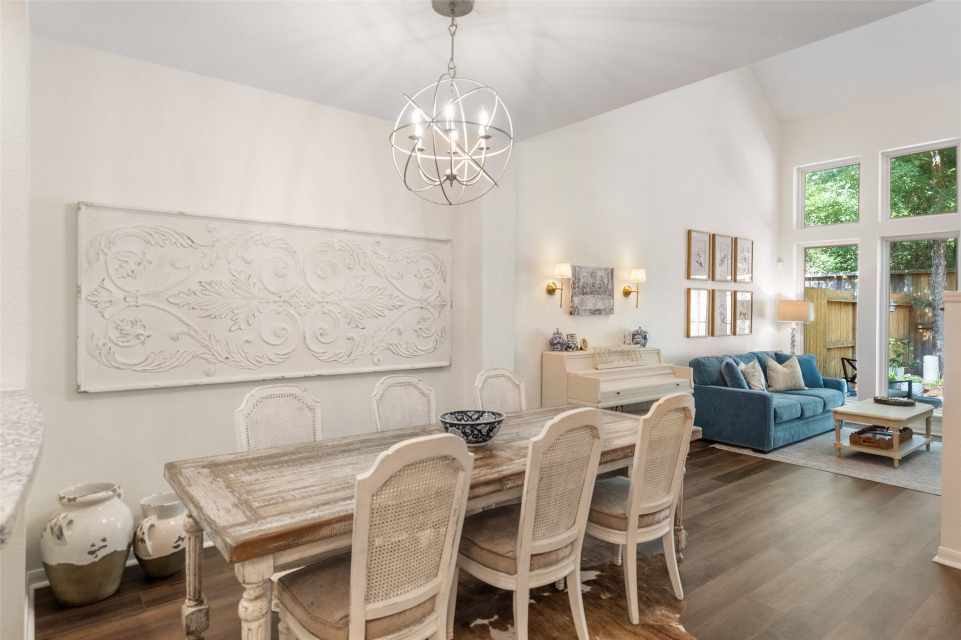 34 Alderon Woods Place, The Woodlands, TX 77382 Elegant open-plan living and dining area featuring a stylish chandelier, and cozy seating area with large windows overlooking a lush back yard space!