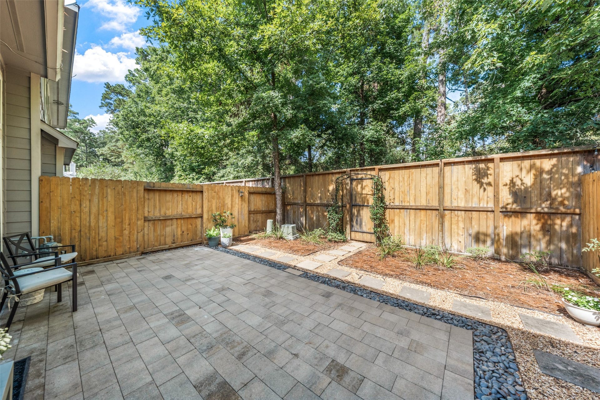34 Alderon Woods Place, The Woodlands, TX 77382 Charming backyard retreat featuring a spacious stone patio, lush greenery, and a private wood fence, perfect for outdoor relaxation and entertaining backs to a greenspace!