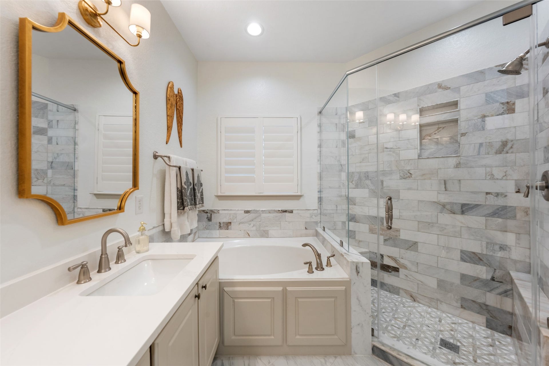 34 Alderon Woods Place, The Woodlands, TX 77382 Elegant updated primary bathroom featuring a luxurious glass-enclosed shower and a soaking tub, complemented by marble tile and stylish fixtures.