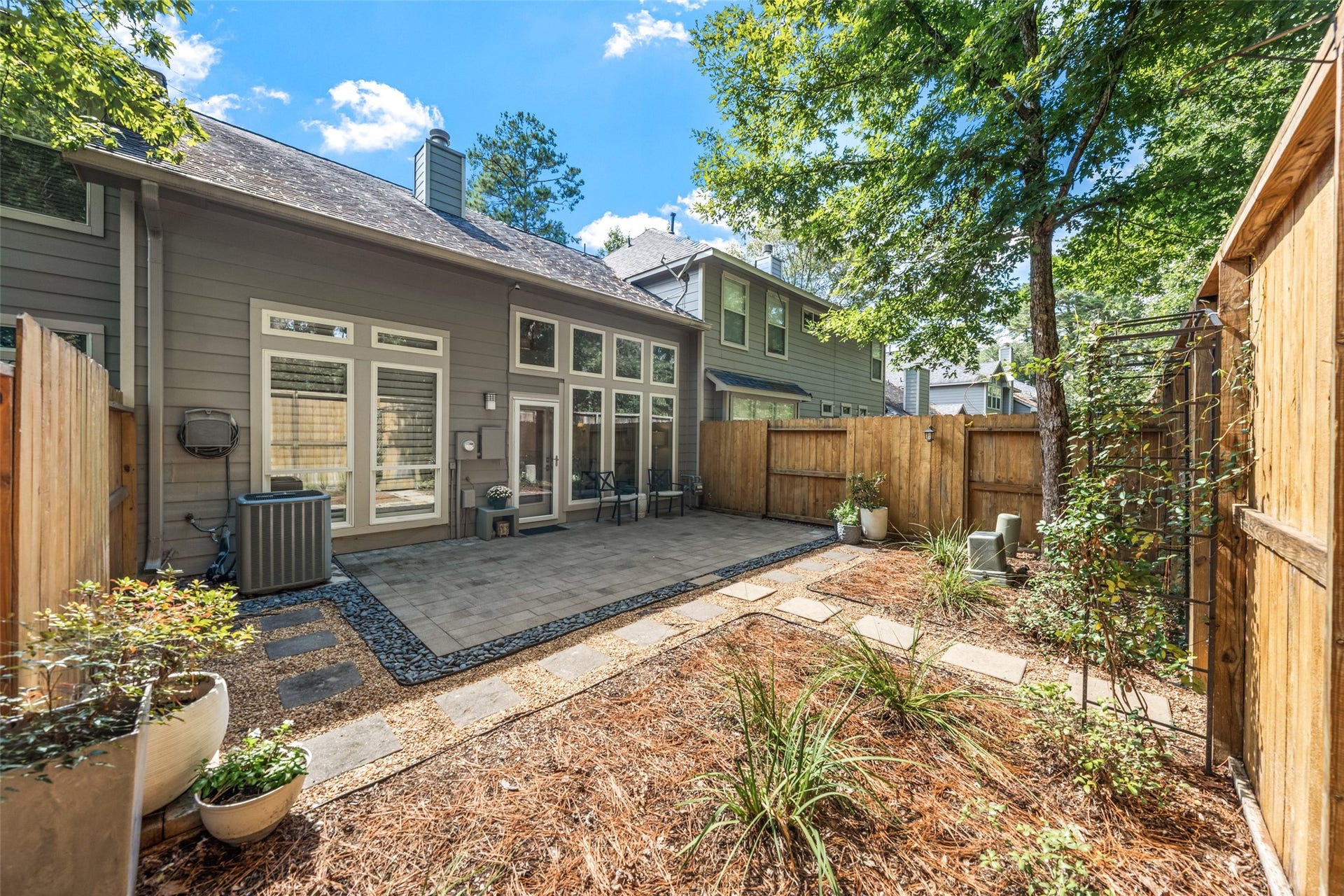 34 Alderon Woods Place, The Woodlands, TX 77382 Charming backyard oasis with a spacious patio, perfect for outdoor entertaining, surrounded by a privacy fence and lush greenery.