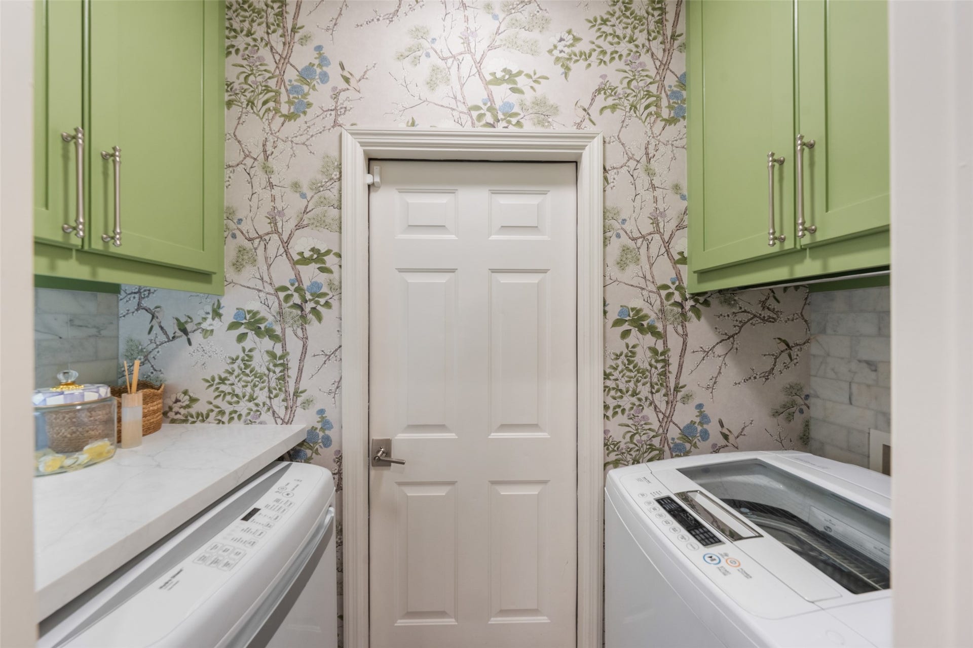 34 Alderon Woods Place, The Woodlands, TX 77382 Charming laundry room featuring vibrant green cabinetry and a nature-inspired wallpaper, creating a fresh and inviting space.