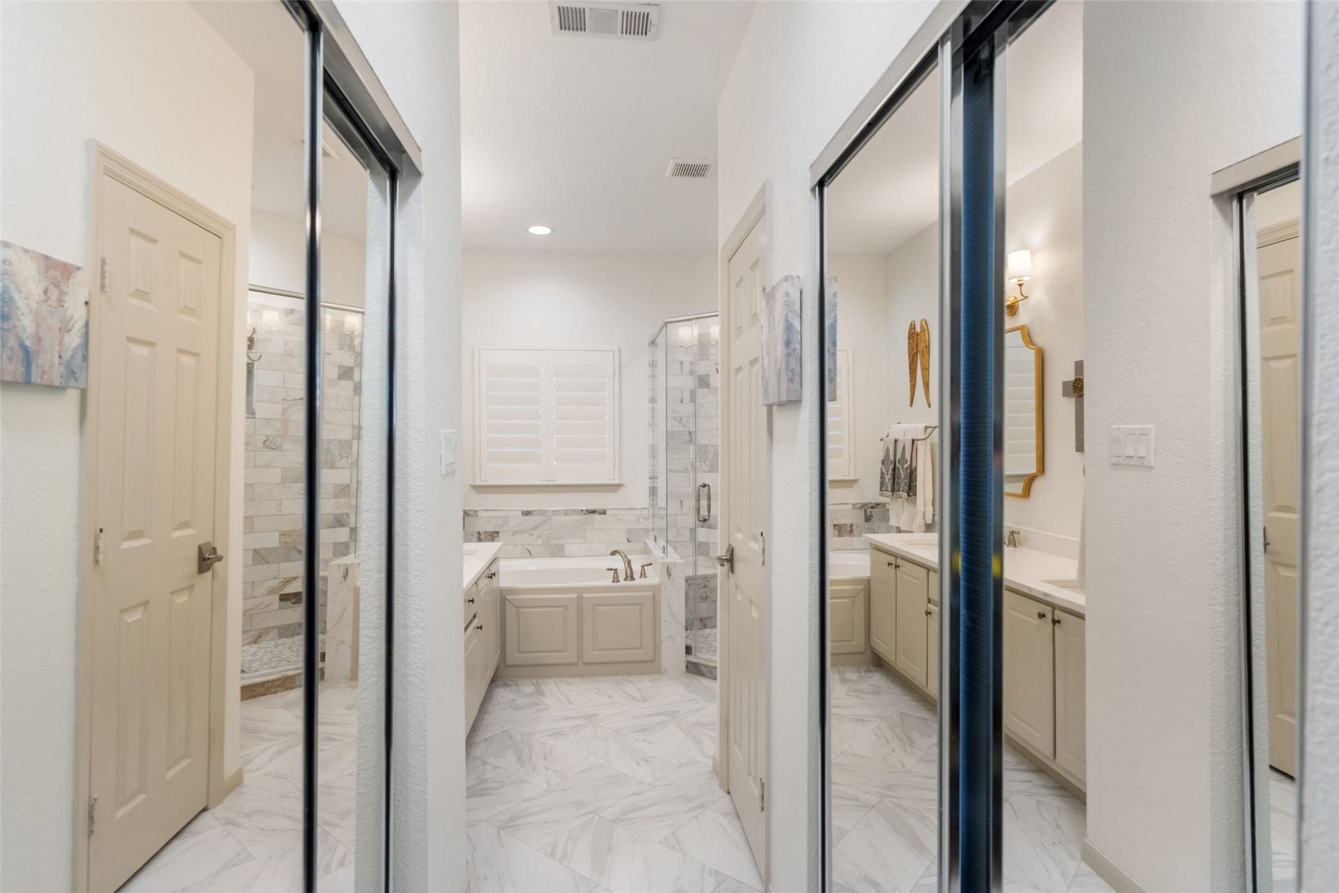 34 Alderon Woods Place, The Woodlands, TX 77382 Elegant bathroom with dual vanities, dual closets, a luxurious soaking tub, and a spacious walk-in shower, all accented by sleek marble tiles and modern fixtures.
