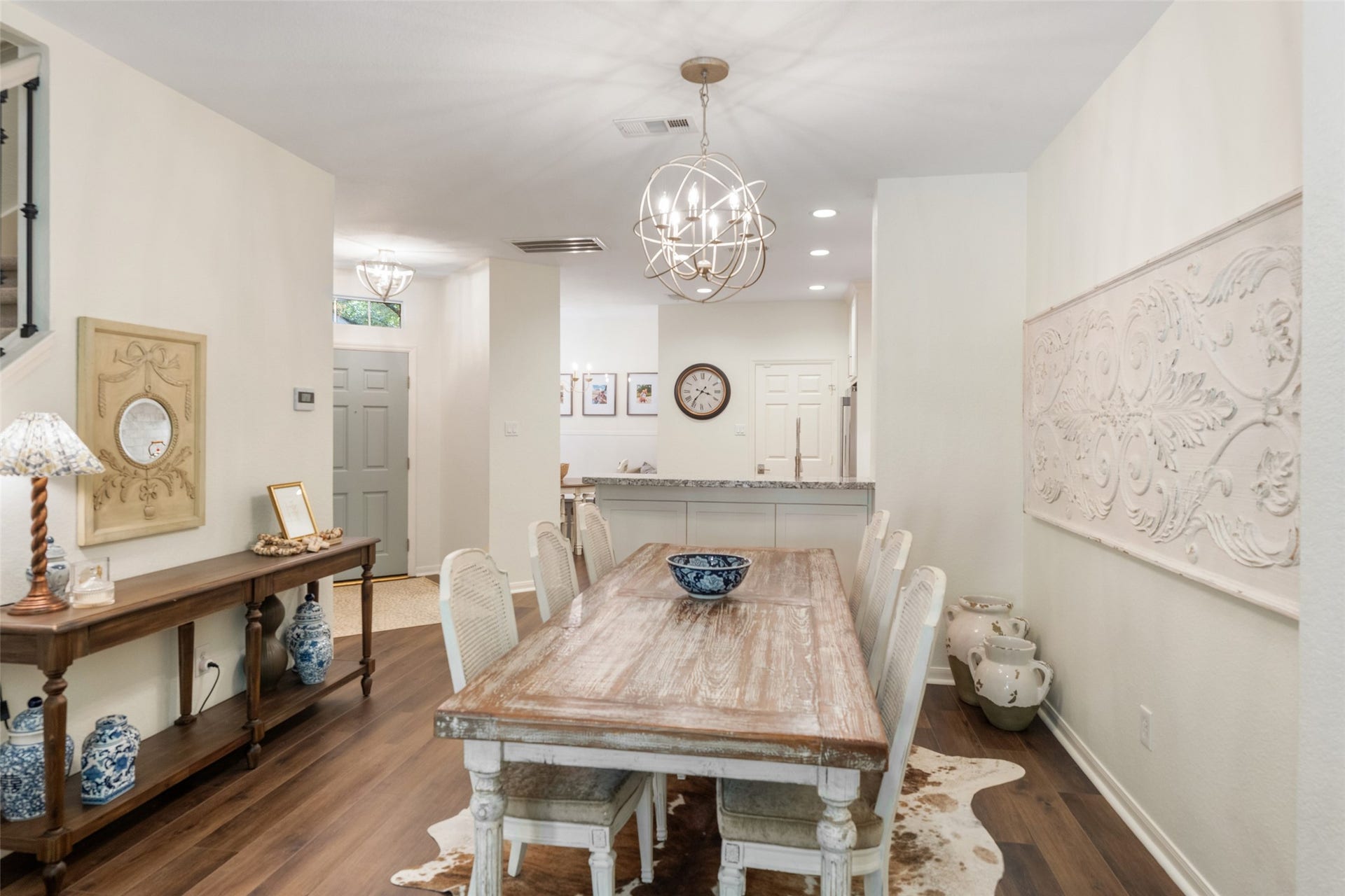 34 Alderon Woods Place, The Woodlands, TX 77382 Charming dining area with a rustic wooden table, elegant chandelier, and stylish decor, seamlessly leading to an open kitchen space.